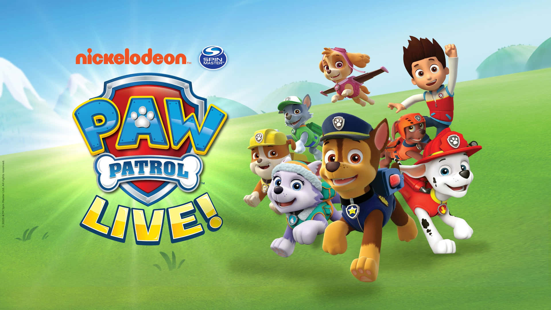 汪汪隊立大功 桌布 壁紙 — Paw Patrol 角色在晴朗藍天和遠處山脈下，在明亮的綠色山丘上快樂奔跑。