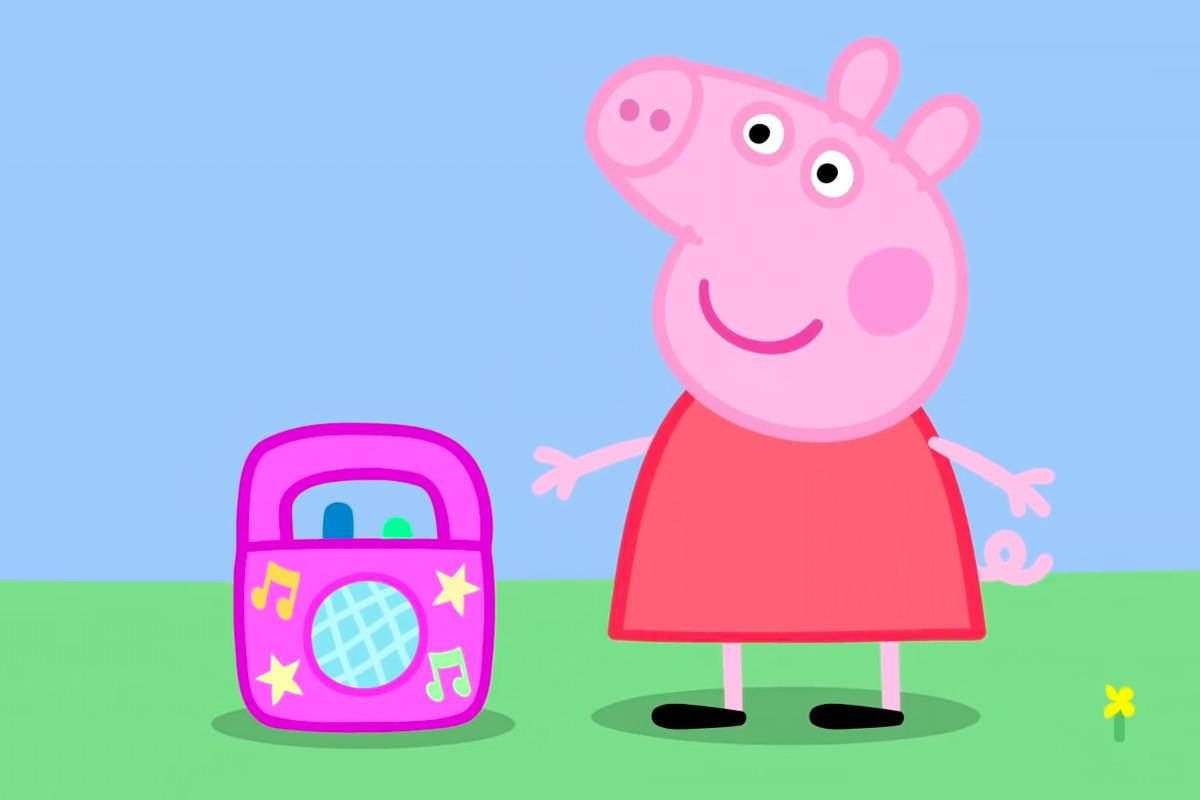 Peppa 桌布 壁紙 — Peppa Pig 在晴朗藍天下的綠色田野上，開心站在粉紅色喇叭旁邊。