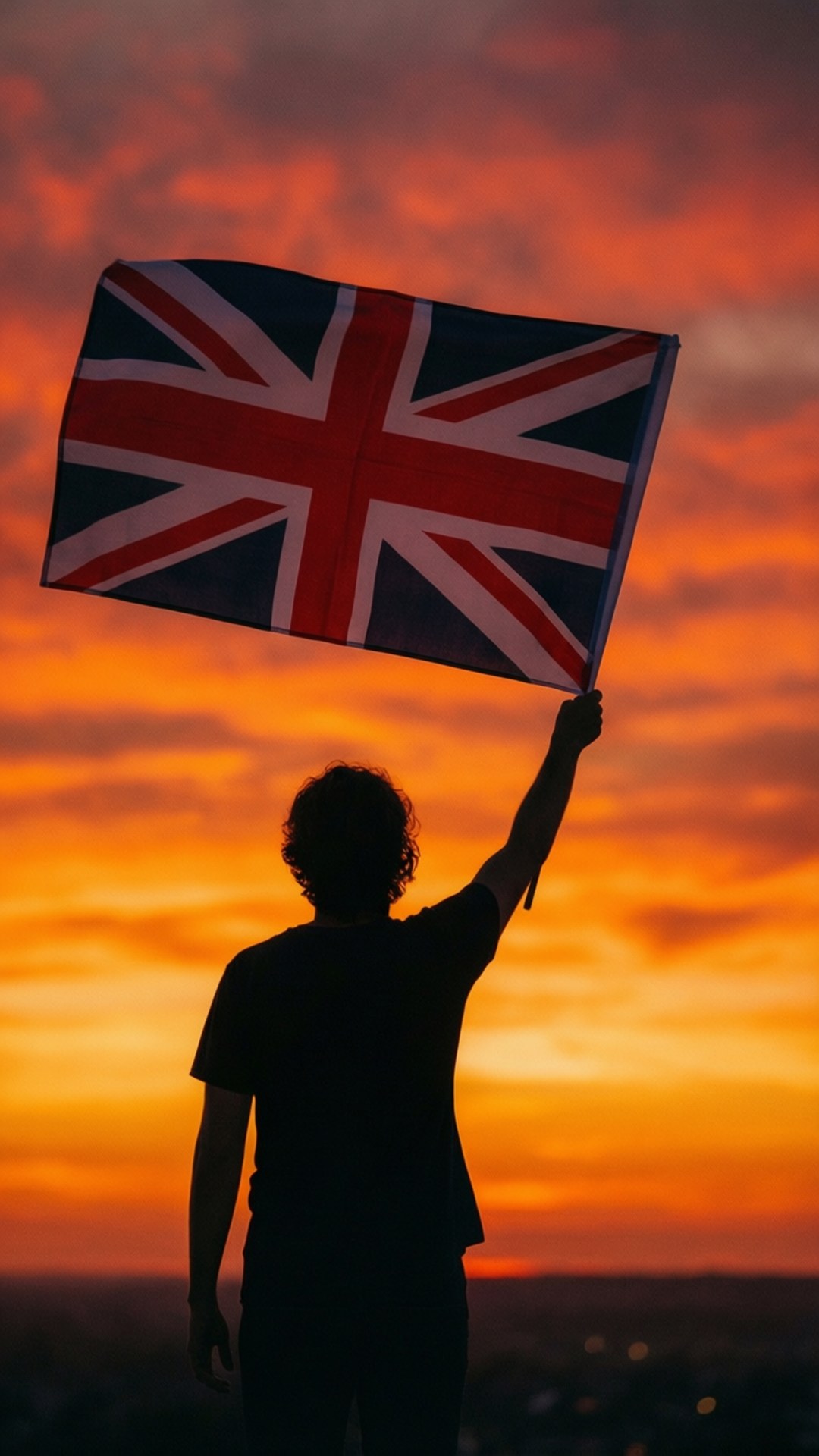 Silhouette with Flag 壁紙 — 一個人以火熱橙色日落為背景形成剪影，在戲劇性的天空中高舉英國國旗。