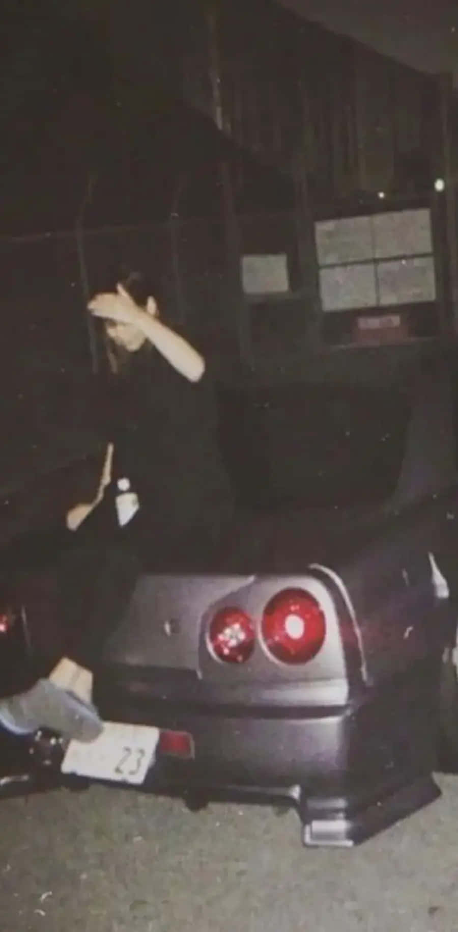  壁紙 — 一個穿黑色衣服的人夜晚坐在一輛深色車上，用一隻手遮住臉。