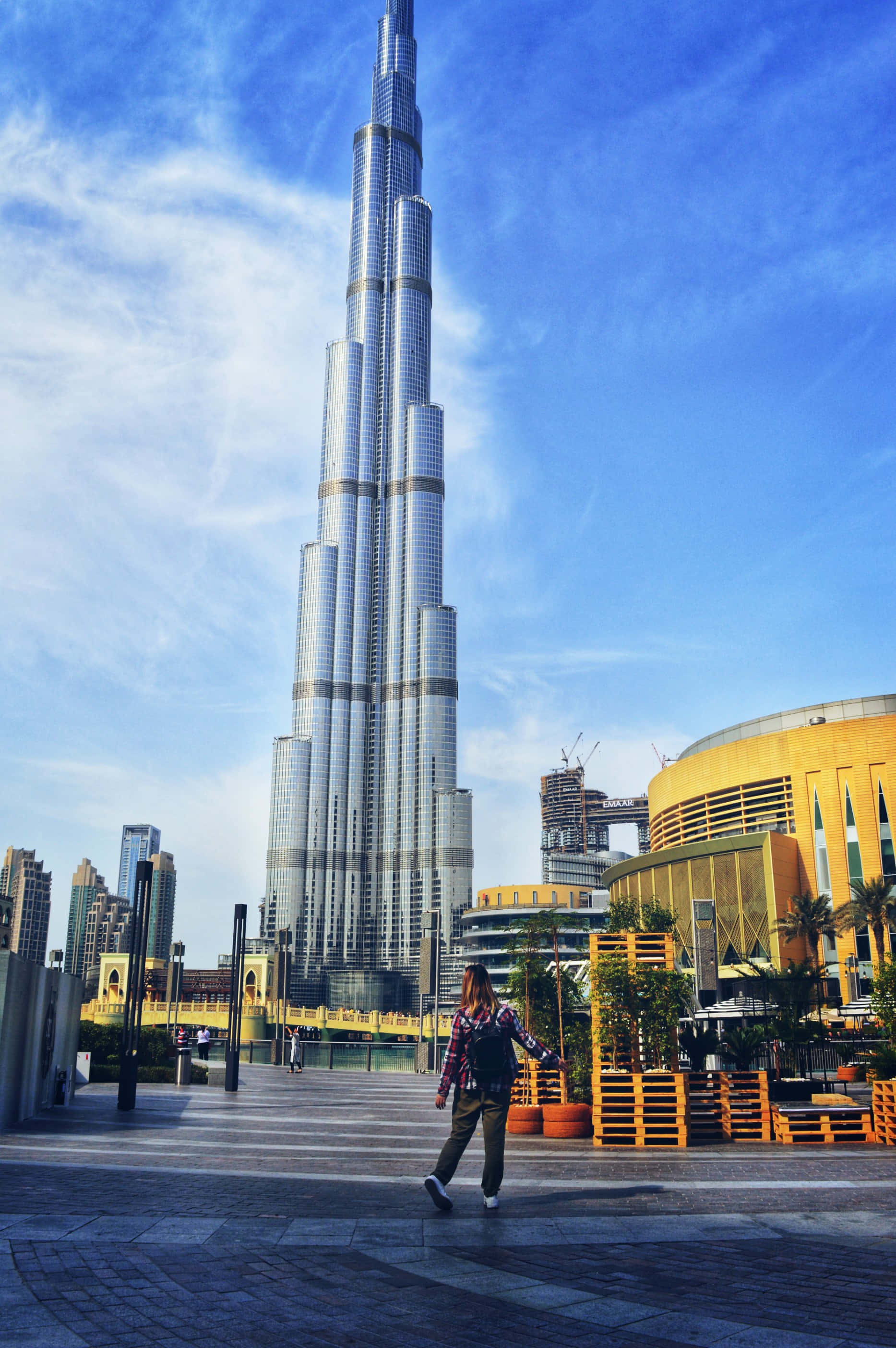 Burj Khalifa 桌布 壁紙 — 一個人在明亮的藍天和薄雲下走向高聳的哈里發塔。