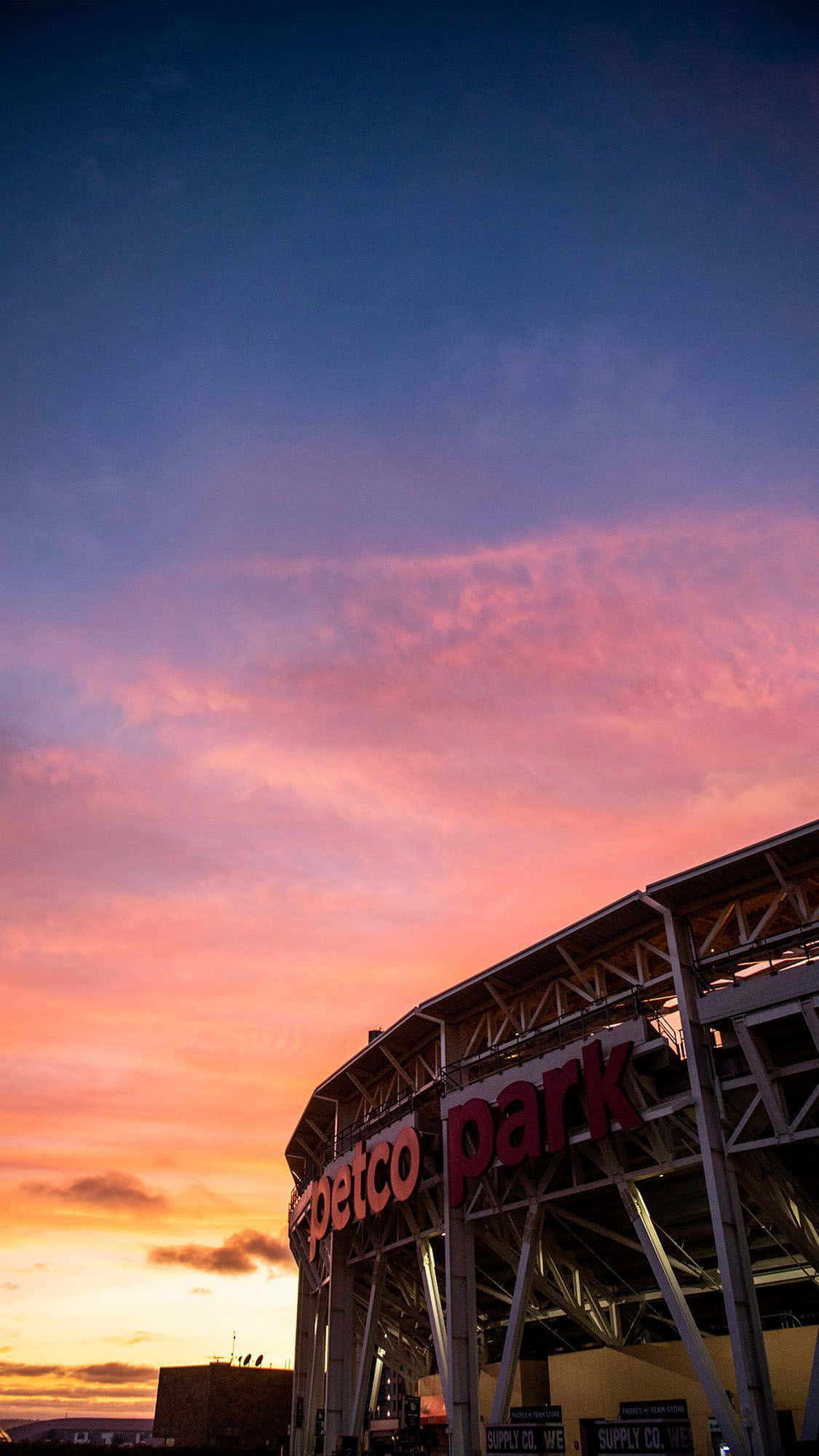 Stadium 桌布 壁紙 — Petco Park 球場的剪影，背景是充滿活力的日落天空，有粉紅色、橙色和藍色的雲彩。