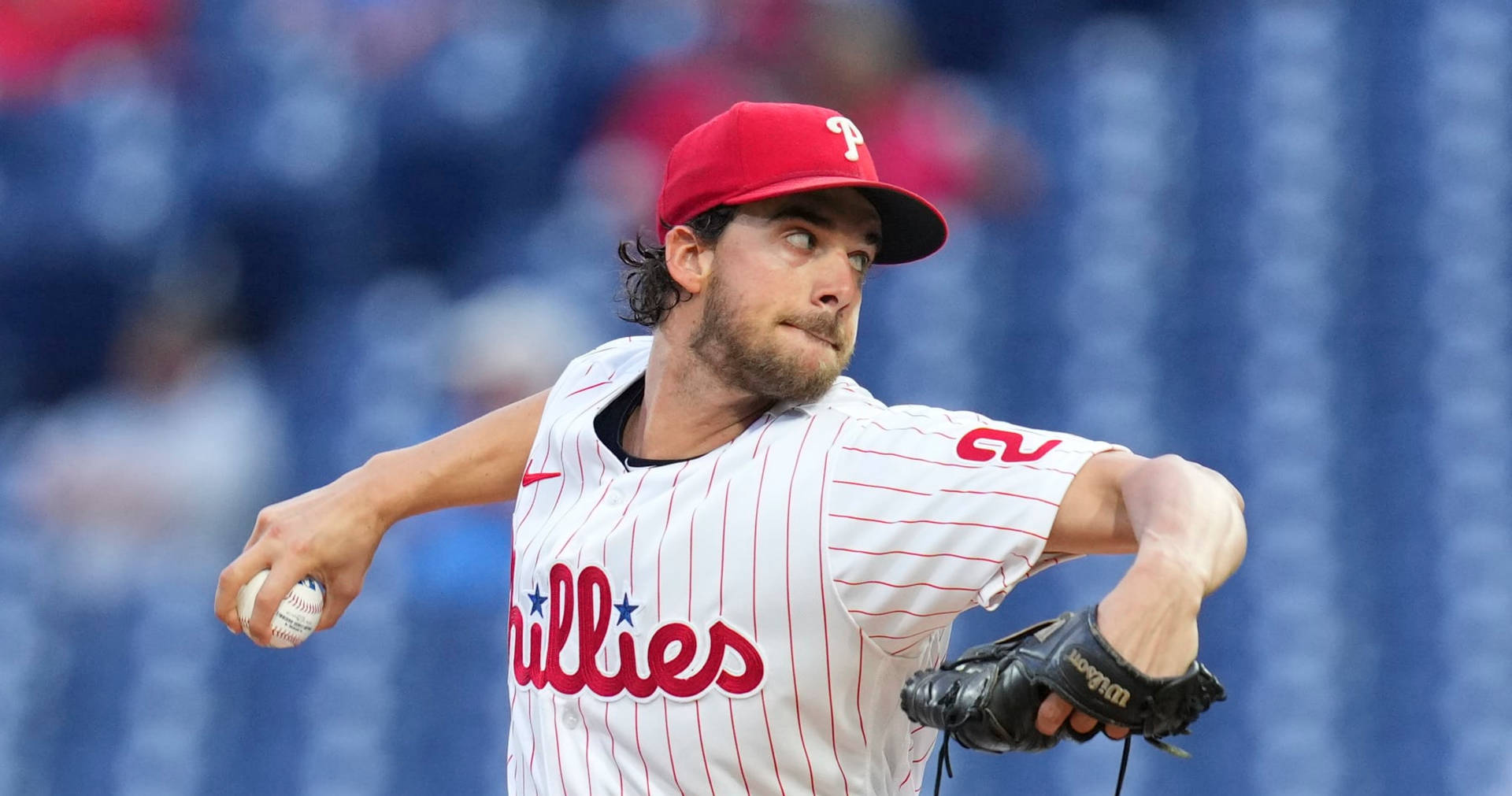 身穿費城人隊球衣的棒球投手在日間比賽中投球。 — MLB 壁紙