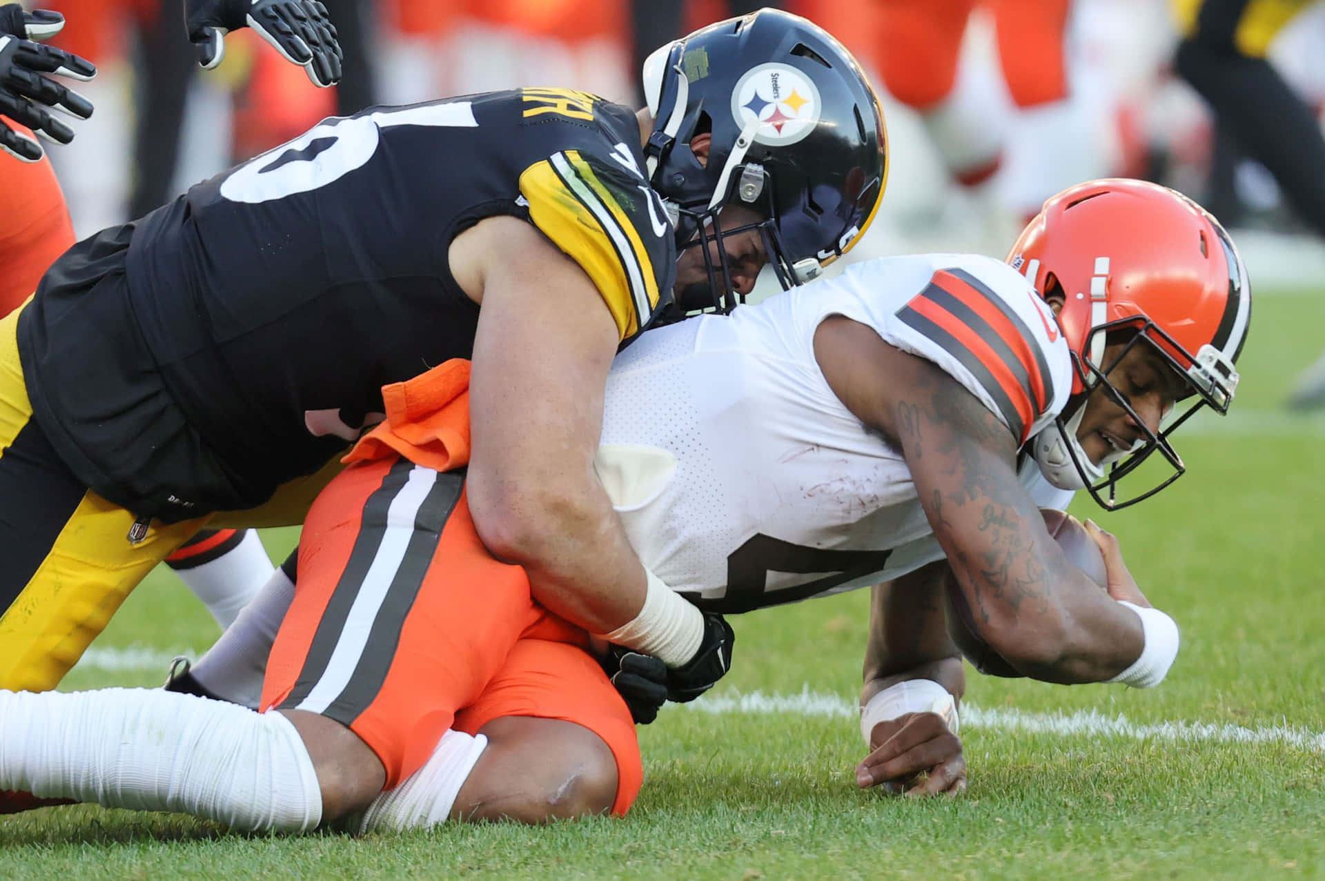  壁紙 — 匹茲堡鋼人隊的線衛在激烈的NFL比賽中於草地上擒抱克里夫蘭布朗隊的四分衛。