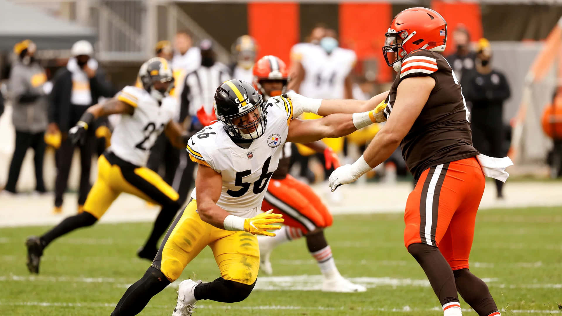  壁紙 — 匹茲堡鋼人隊的線衛在激烈的NFL美式足球比賽中擒抱克里夫蘭布朗隊的進攻鋒線球員。