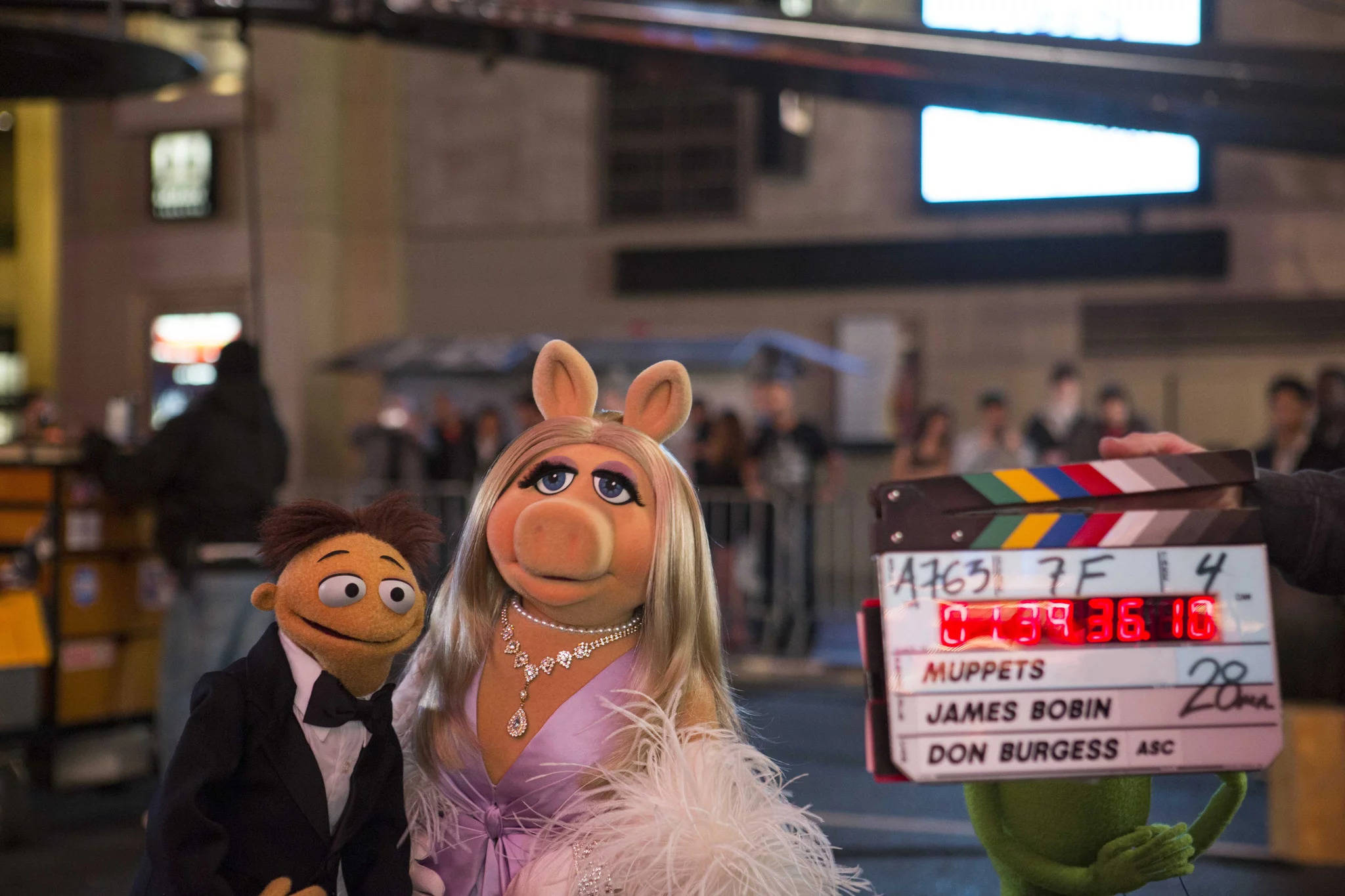 muppets 桌布 壁紙 — Piggy 和 Kermit 在明亮的攝影棚燈光下，於電影佈景中拿著場記板擺姿勢。