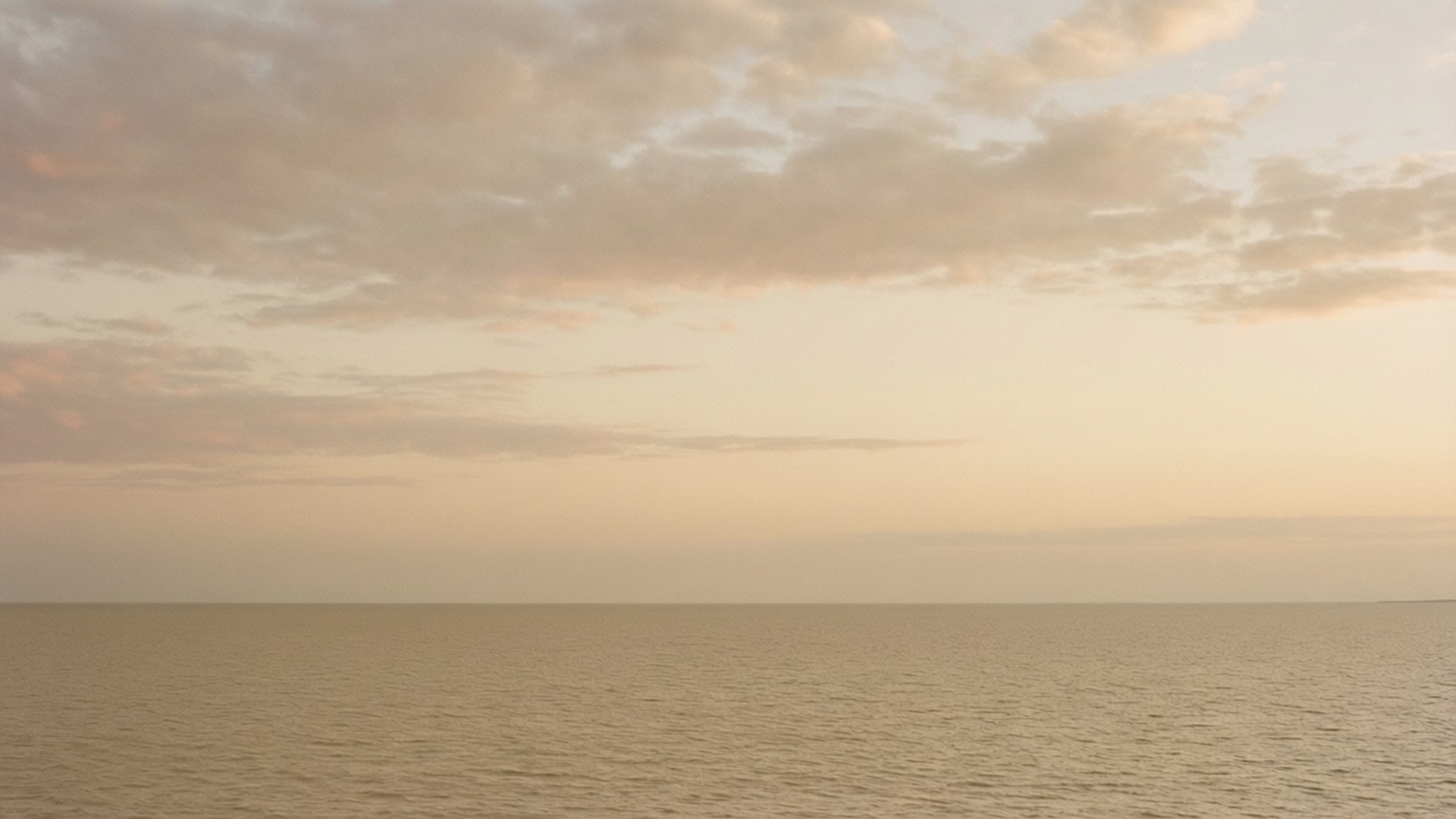 Beige Twilight Seascape 壁紙 — 平靜的地平線，平靜的海洋在黎明或黃昏與柔和的桃色和奶油色天空相遇。