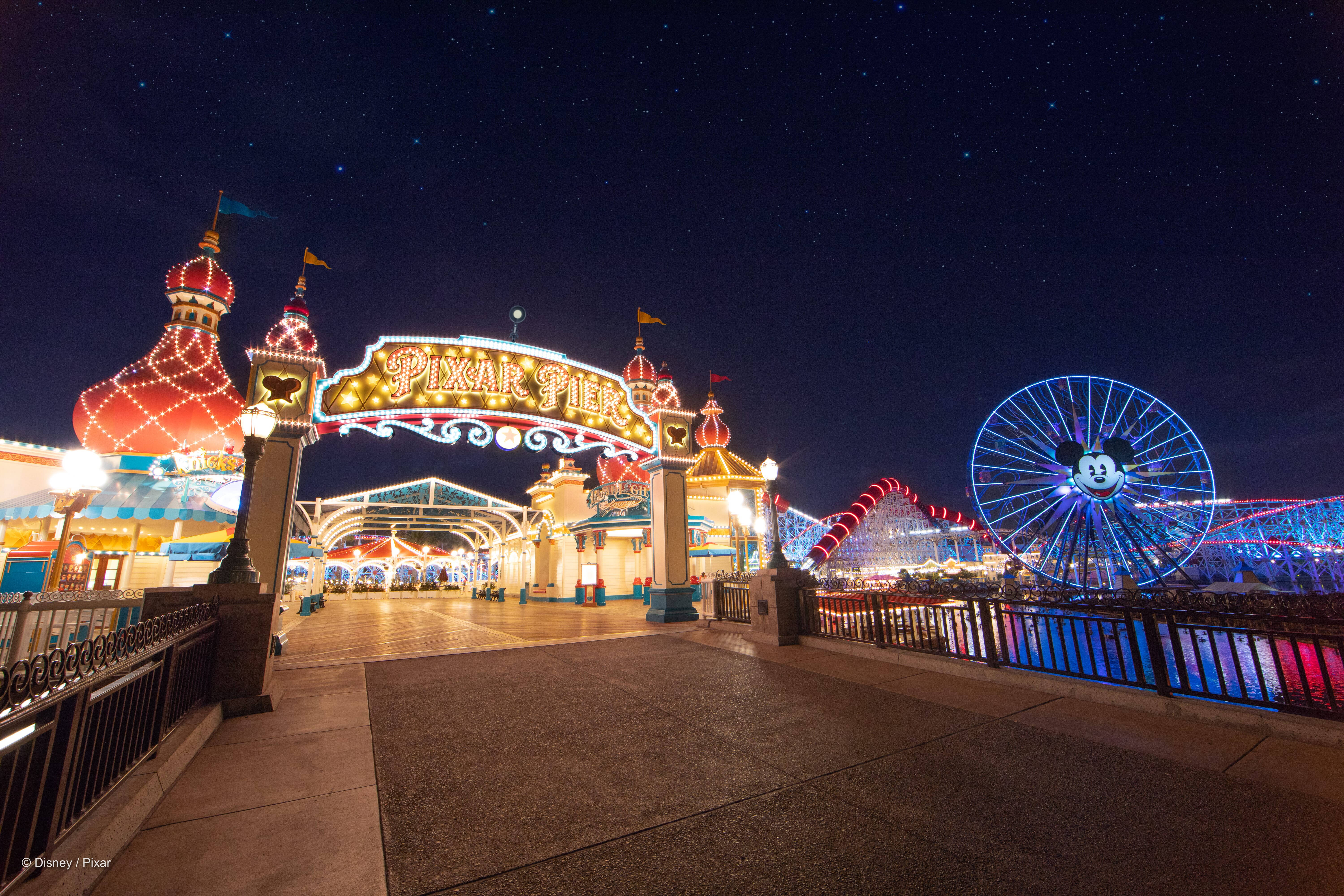 迪士尼 桌布 壁紙 — Pixar Pier 在夜晚星空下閃耀，有米奇老鼠摩天輪和色彩繽紛的遊樂設施。