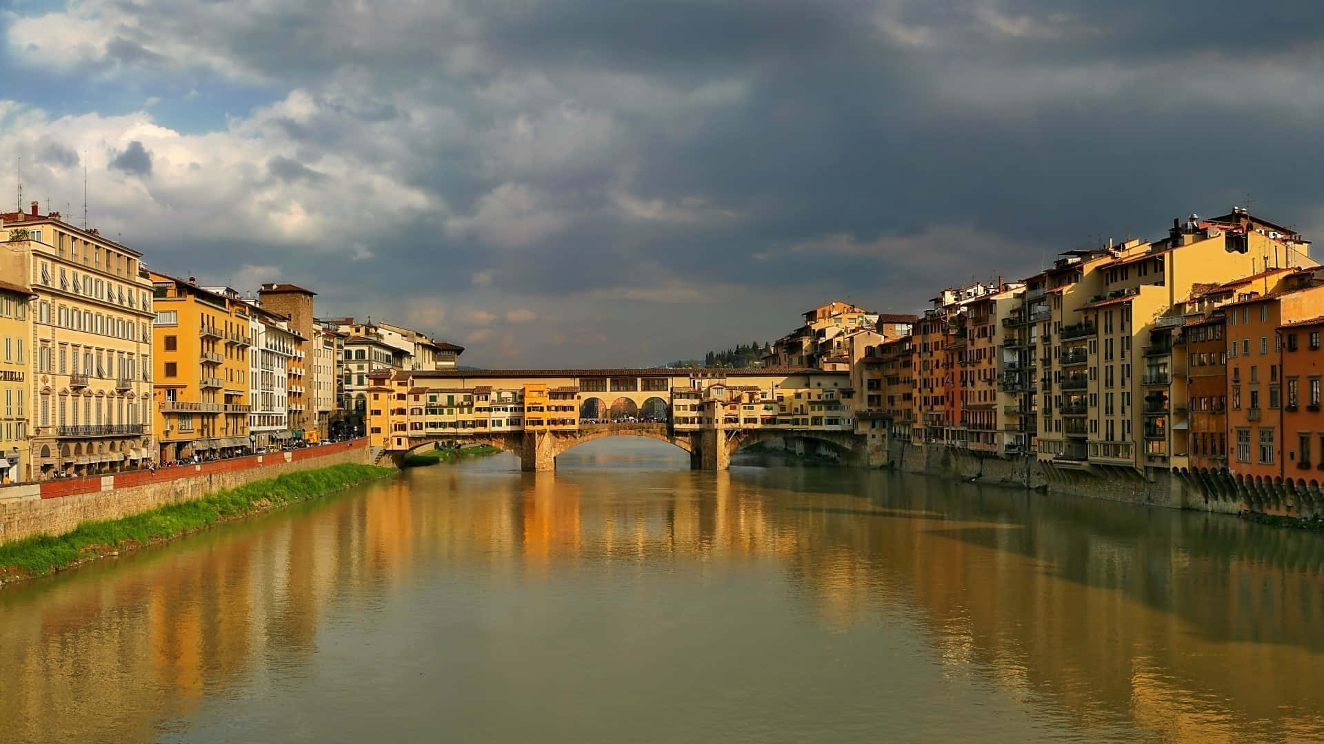 Building 桌布 壁紙 — Ponte Vecchio橋橫跨阿諾河，在戲劇性的多雲天空下，歷史建築倒映在水中。