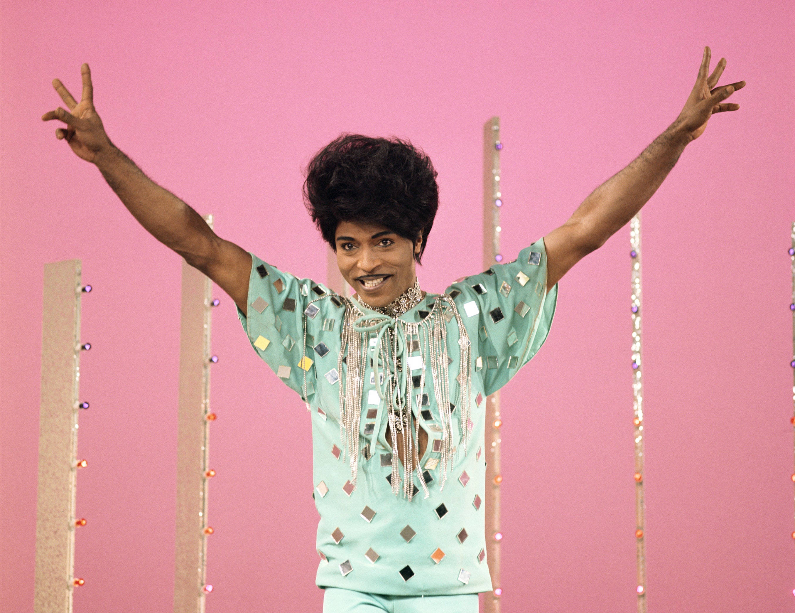 Celebrity 桌布 壁紙 — Prince 以閃閃發光的薄荷綠色服裝，在充滿活力的粉紅色背景和閃爍的垂直桿前擺出歡樂的姿勢。