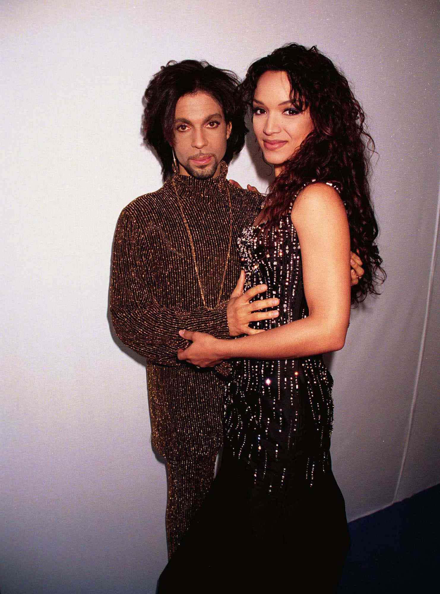 王子 桌布 壁紙 — Prince 與 Mayte Garcia 在純色攝影棚牆前，身穿華麗珠飾服裝擁抱。