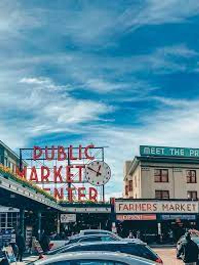 Pike Place Market 桌布 壁紙 — Public Market Center 充滿活力的霓虹招牌在晴朗藍天和零星白雲下閃耀。