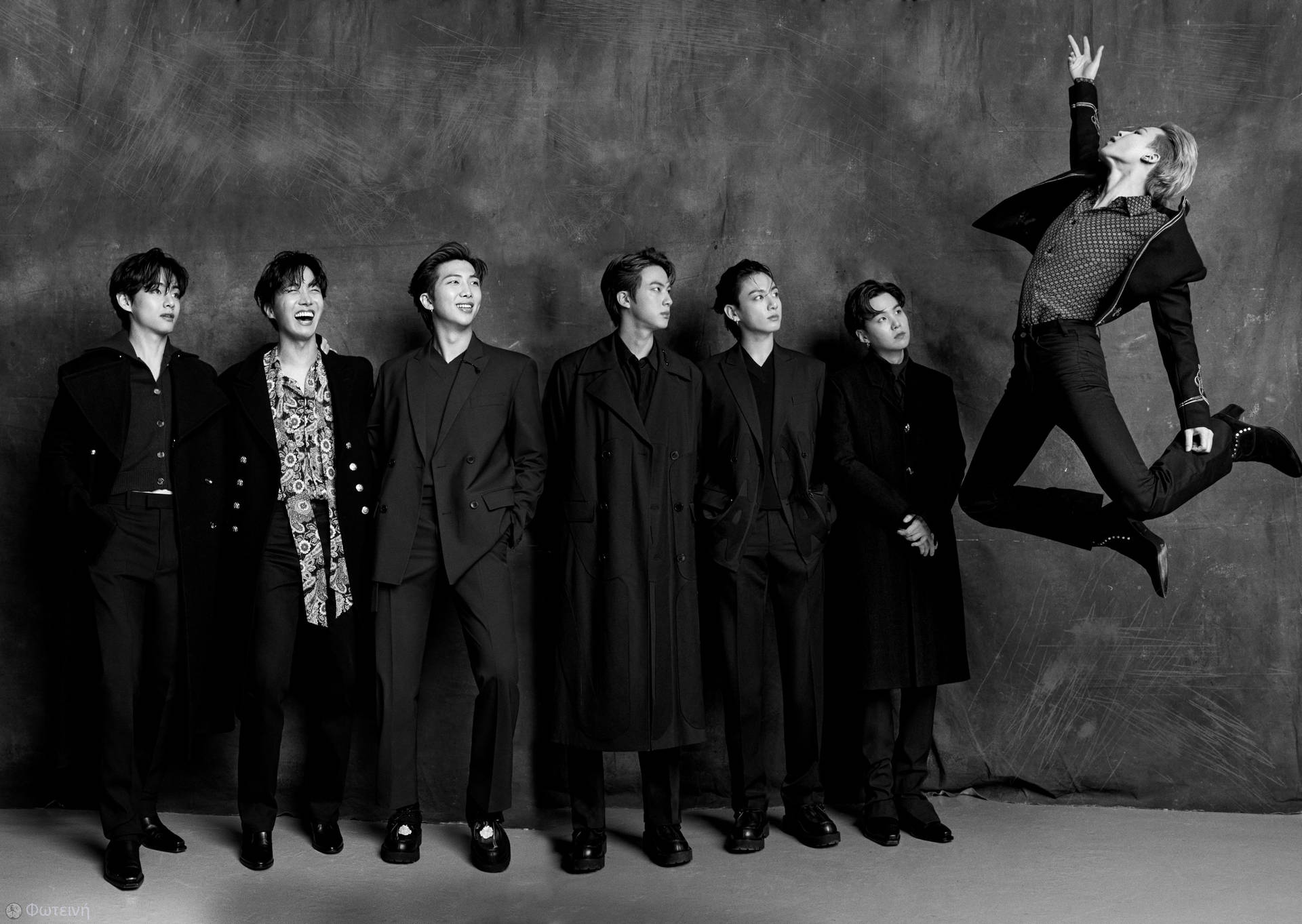 七個穿深色大衣的男人，一個在工作室肖像中騰空跳躍。 — Bts 壁紙