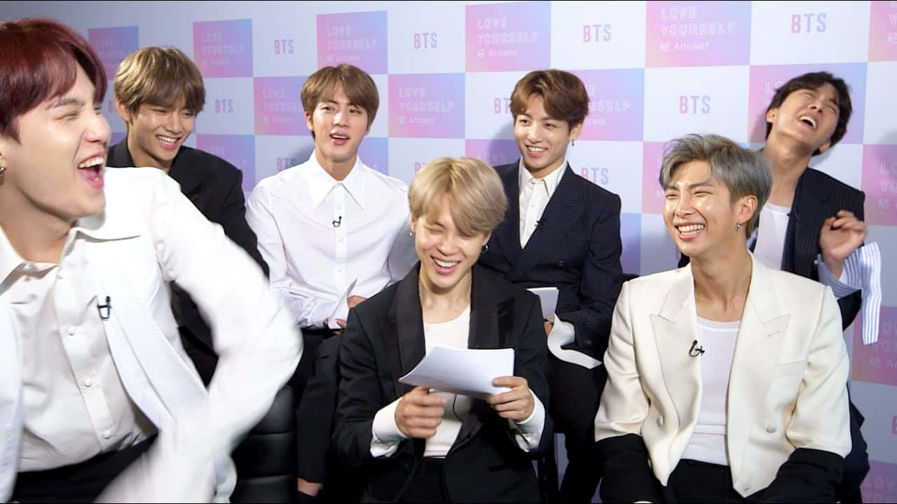 七位穿著西裝的K-pop偶像在記者會上大笑。 — Bts 壁紙