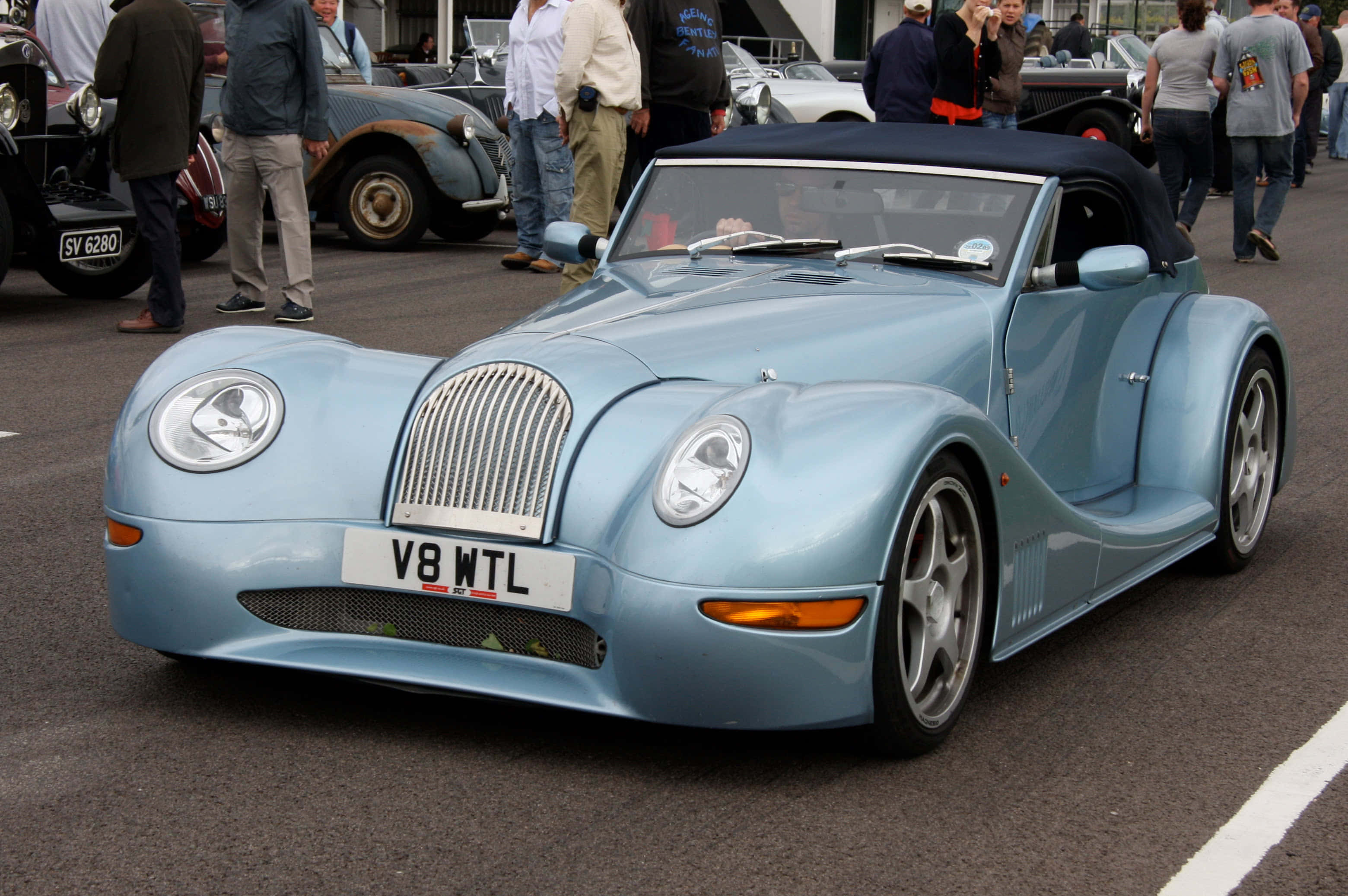 Morgan Aero 8 桌布 壁紙 — 一輛淺藍色經典敞篷跑車配黑色軟頂停放在車展中，周圍有觀眾。