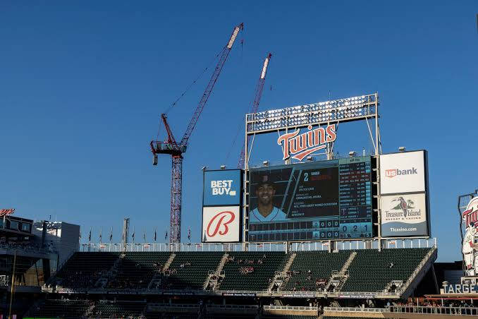 棒球場記分板在清澈藍天下顯示Twins比賽數據，座位空蕩。 — MLB 壁紙