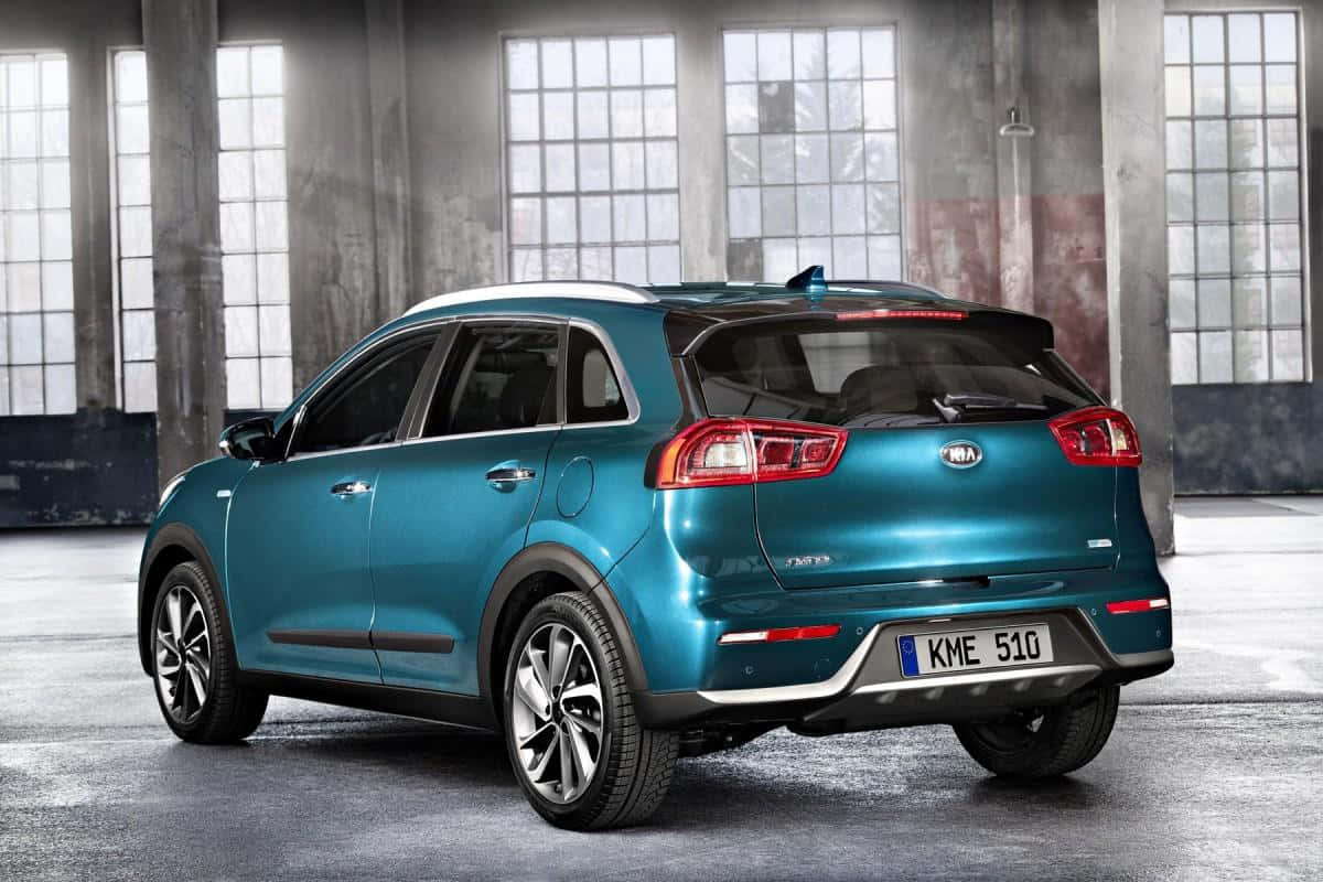 Kia Niro 桌布 壁紙 — 一輛青綠色的Kia Niro EV SUV停放在一個寬敞的工業倉庫內，倉庫有大窗戶和混凝土柱。