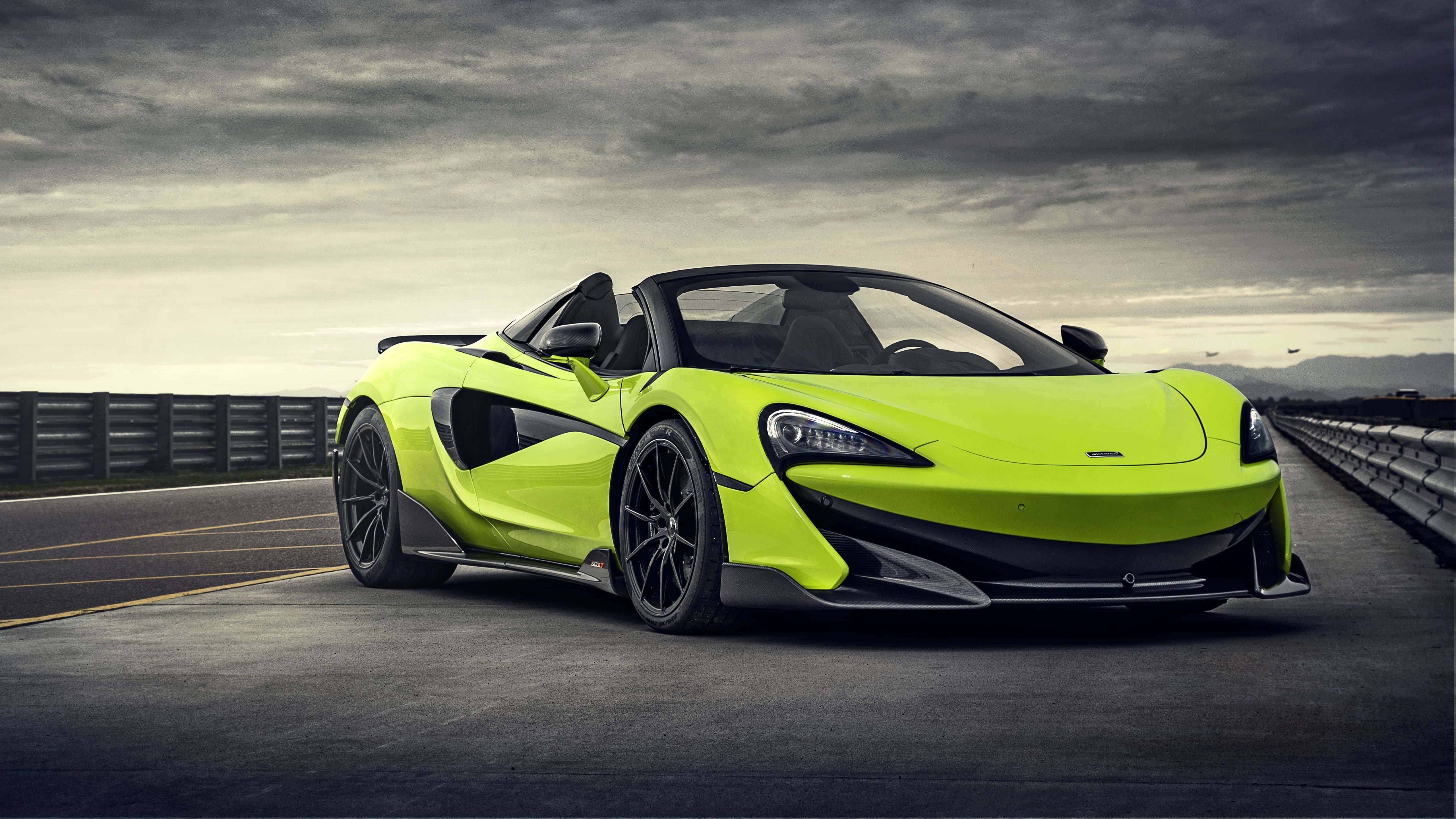 Mclaren 600lt 桌布 壁紙 — 一輛鮮豔的青檸綠色McLaren 570S Spider跑車停放在陰沉多雲的天空下的高速公路上。