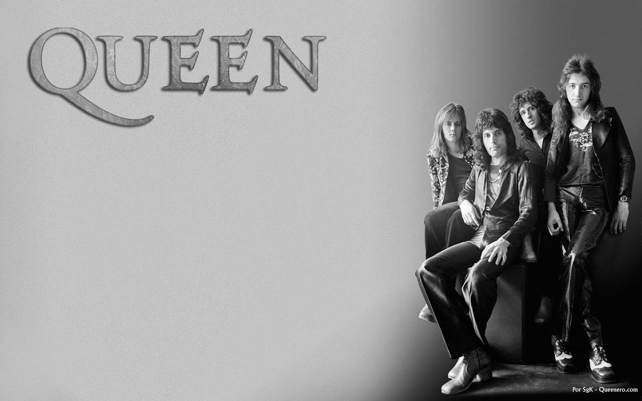 女王 桌布 壁紙 — Queen 樂團的四位成員以黑白風格在一面素牆前擺姿勢，樂團名稱以風格化字體印在他們上方。
