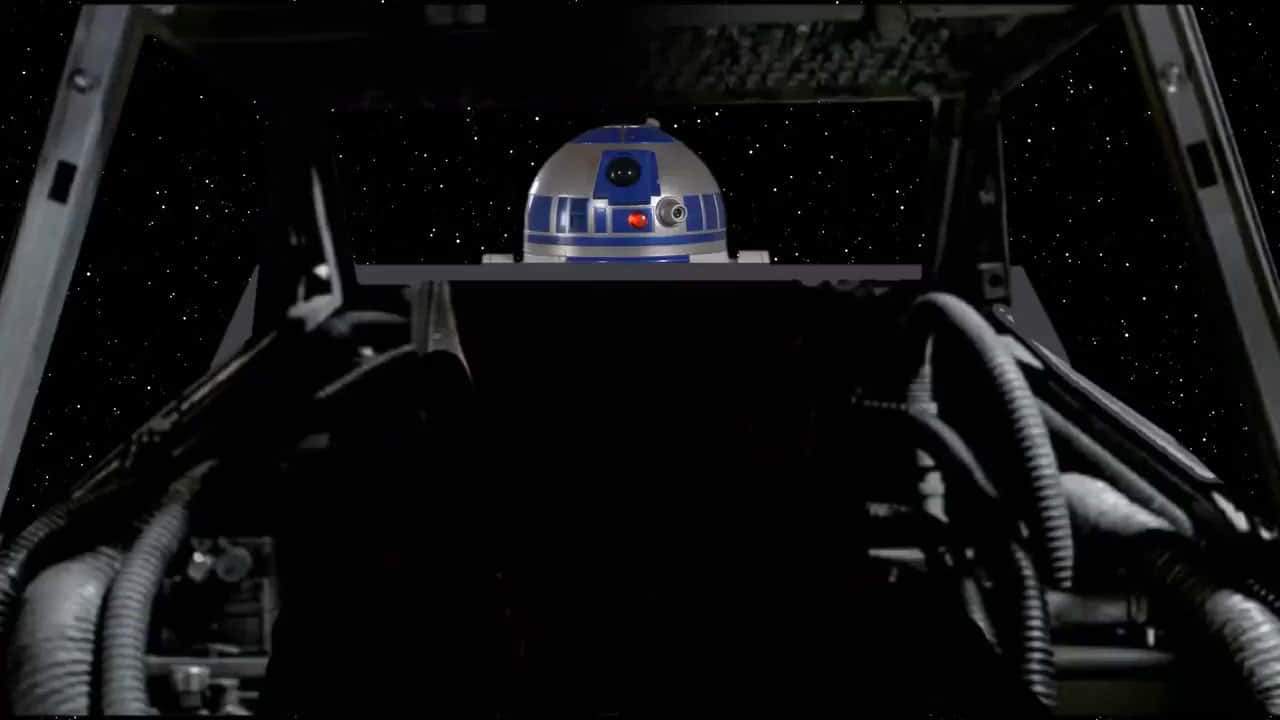 星際大戰 桌布 壁紙 — R2-D2 坐在太空船駕駛艙內，透過後面的窗戶可以看到星星。