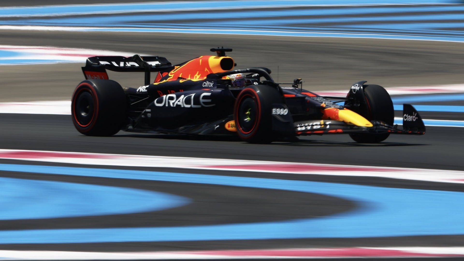 紅牛F1賽車在賽道上行駛，帶有動態模糊效果 — F1 壁紙