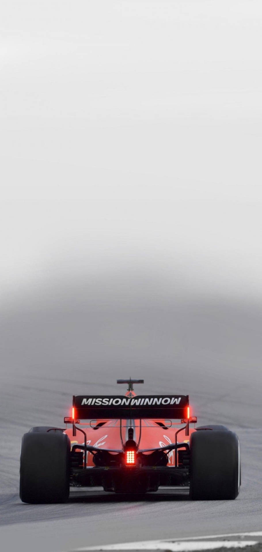 紅色F1賽車在霧濛濛的賽道上疾馳，尾燈閃爍。 — F1 壁紙