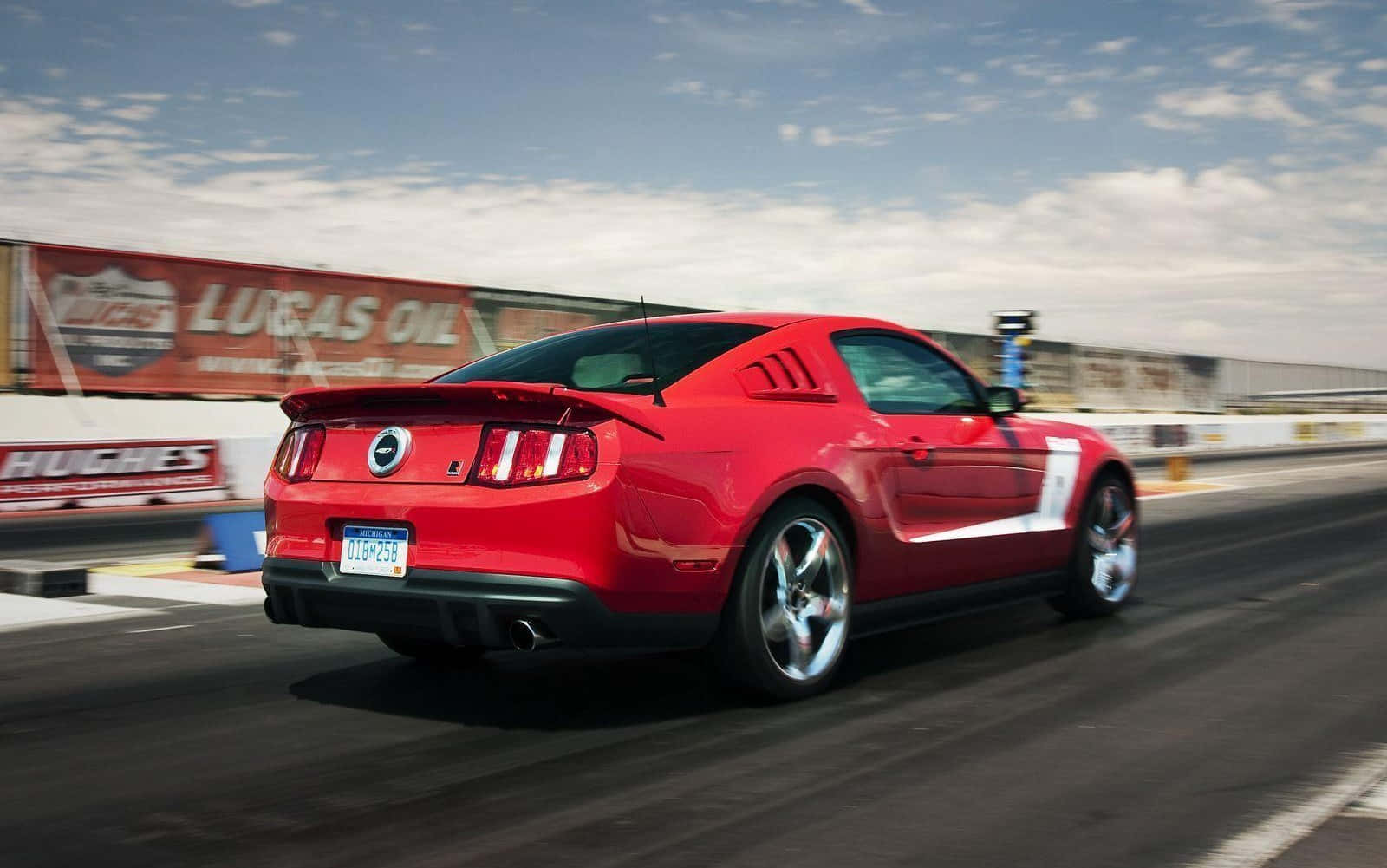 Ford Mustang Roush 桌布 壁紙 — 一輛鮮紅色的福特野馬在直線加速賽道上奔馳，動態模糊效果傳達出高速感，天空局部多雲。