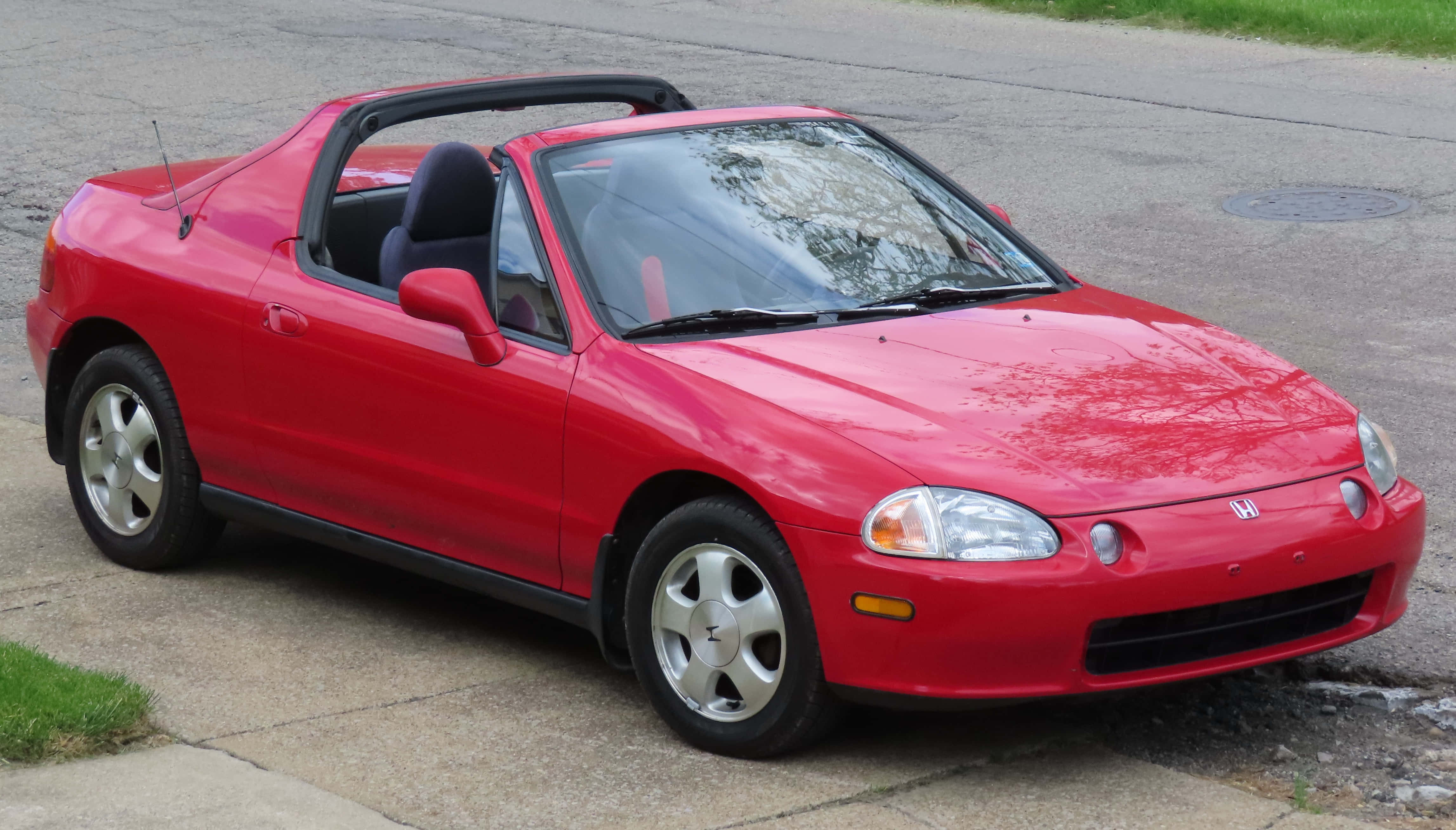Honda Civic Del Sol 桌布 壁紙 — 一輛鮮紅色的本田 Del Sol 敞篷車停放在附近有草地和路面的行人道上。