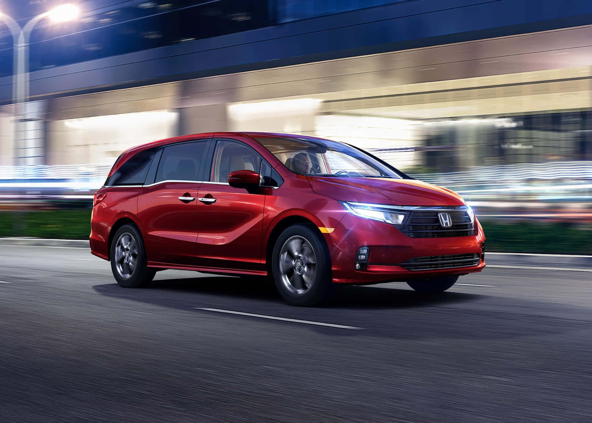 Honda Odyssey 桌布 壁紙 — 一輛鮮紅色的本田小型貨車在發光的街燈下，穿過模糊的都市夜景高速行駛。