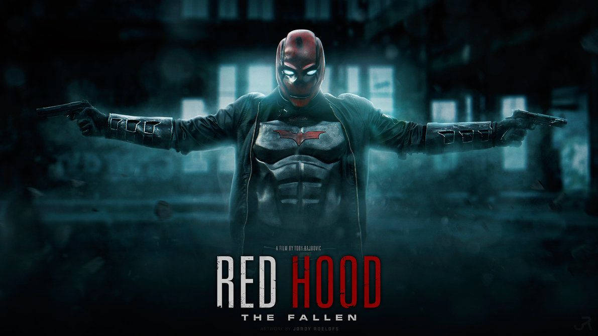 紅頭罩 桌布 壁紙 — Red Hood 站在黑暗的城市廢墟中，雙臂伸展持槍，發光的眼睛和紅色頭罩，背景是霧藍色。