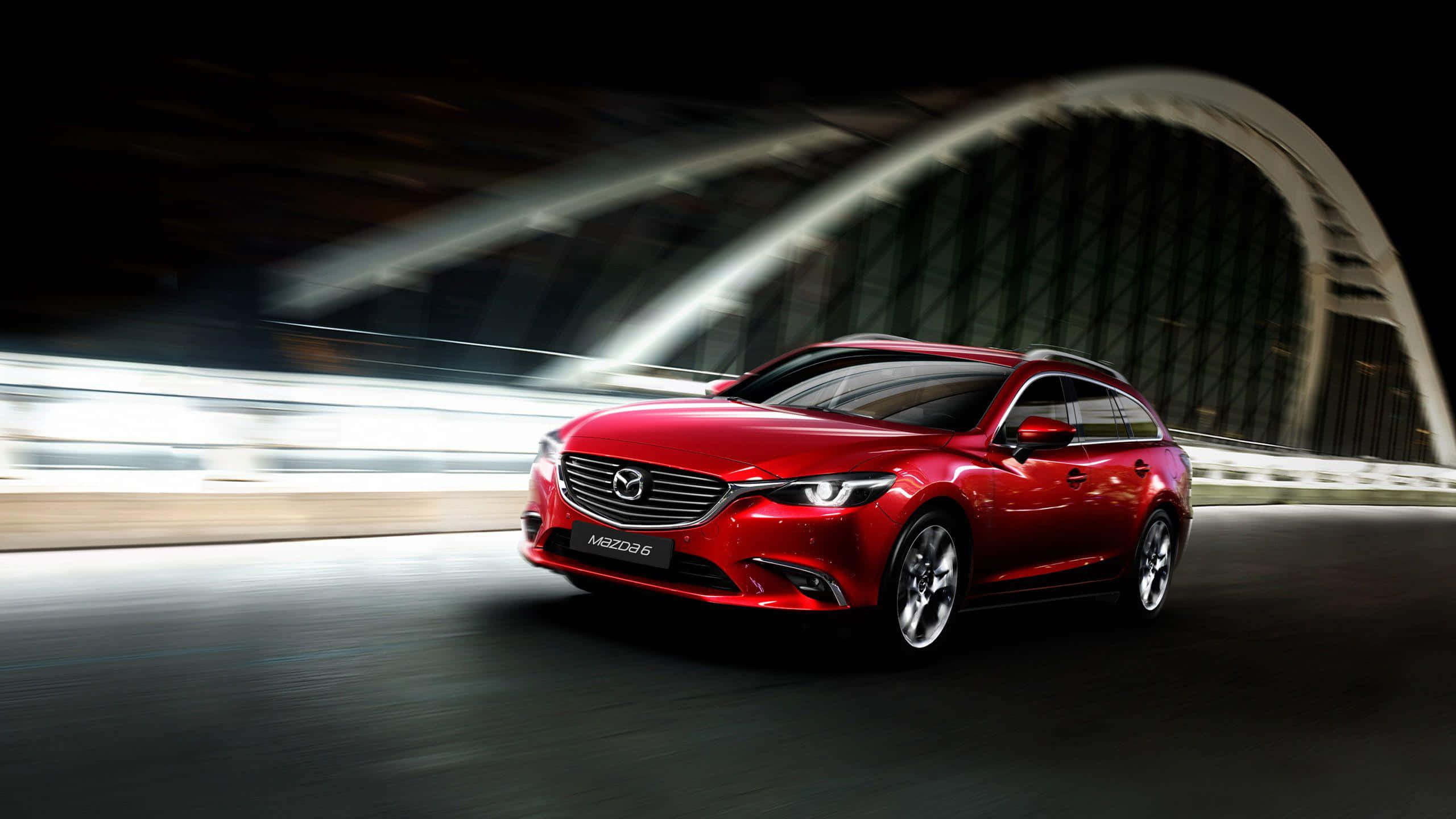 Mazda 6 桌布 壁紙 — 一輛鮮紅色的馬自達6旅行車在夜間於發光的拱橋下高速行駛，帶有動態模糊條紋。