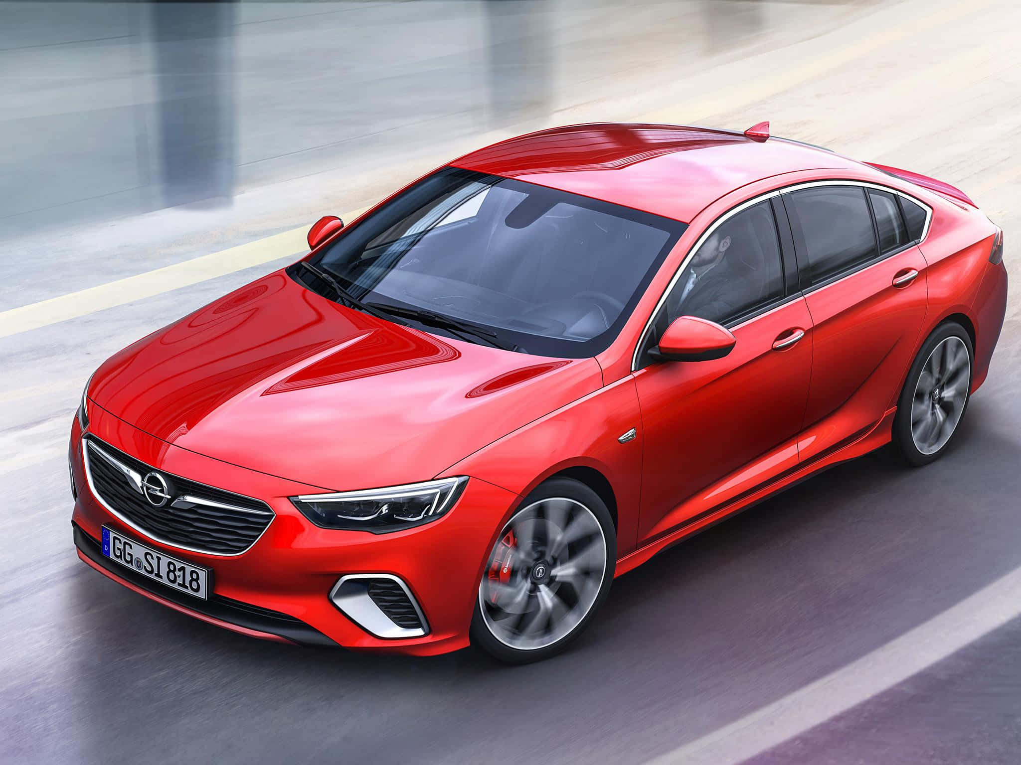 Opel Insignia 桌布 壁紙 — 一輛鮮紅色的歐寶Insignia在模糊的城市道路上疾駛，動態模糊強調其流線型空氣動力學設計。