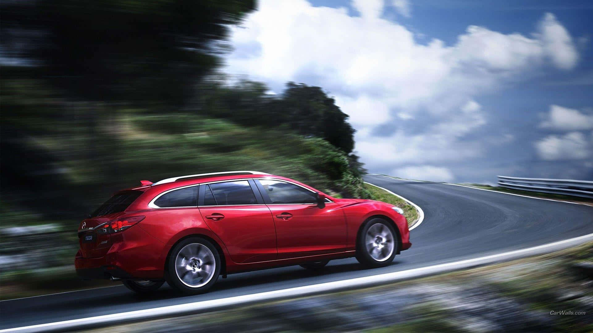 Mazda 6 桌布 壁紙 — 一輛鮮紅色的旅行車在藍天白雲下沿著蜿蜒的山路飛馳。