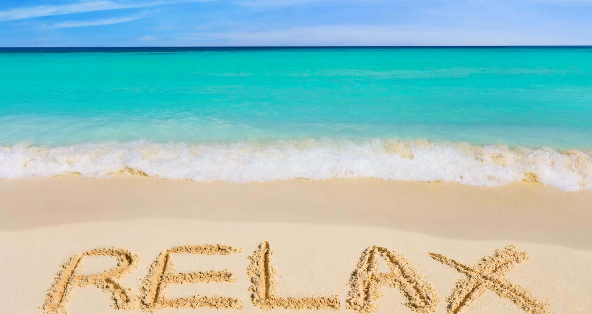 Cute Beach 桌布 壁紙 — 「relax」這個字寫在純淨沙灘的沙上，碧藍色海浪在晴朗藍天下翻滾。