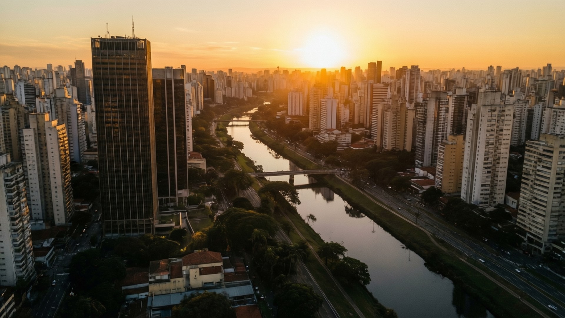 São Paulo Sunset River View 壁紙 — 日落時分廣闊城市景觀的鳥瞰圖，金色光線照亮摩天大樓和下方蜿蜒的河流。