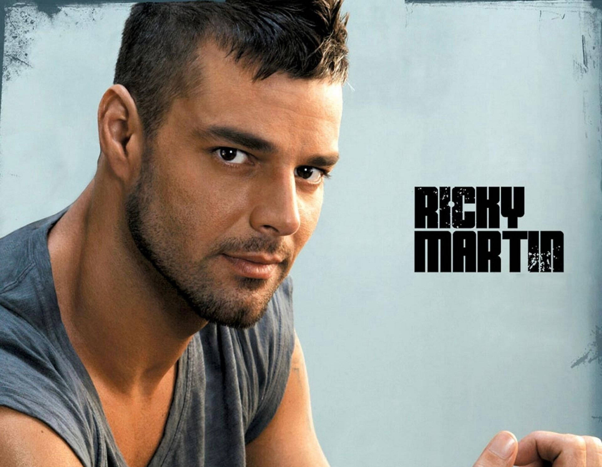 瑞奇·馬丁 桌布 壁紙 — Ricky Martin 在帶有紋理的淺藍色背景上，以粗體黑色文字，強烈地凝視著觀眾。