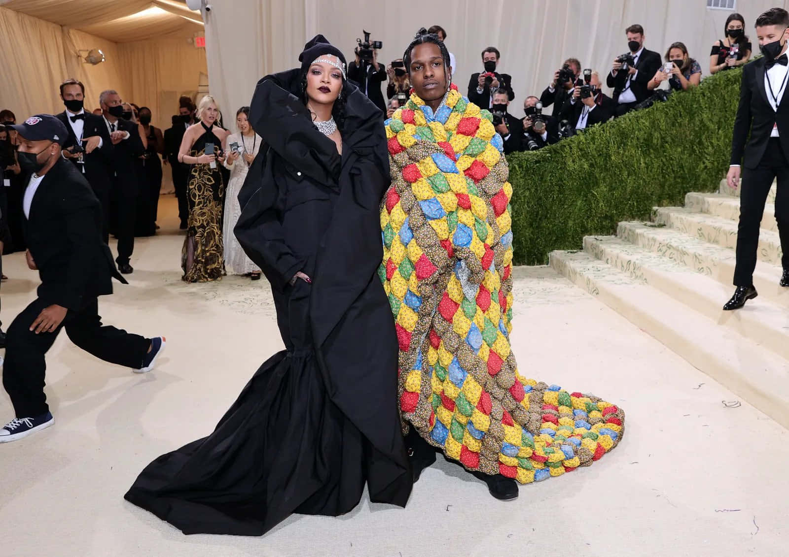 Met Gala 2021 桌布 壁紙 — Rihanna 和 A$AP Rocky 在 Met Gala 上以大膽時尚造型亮相，Rihanna 穿著戲劇性的黑色禮服，A$AP Rocky 則穿著色彩繽紛的鉤針編織毯子套裝。