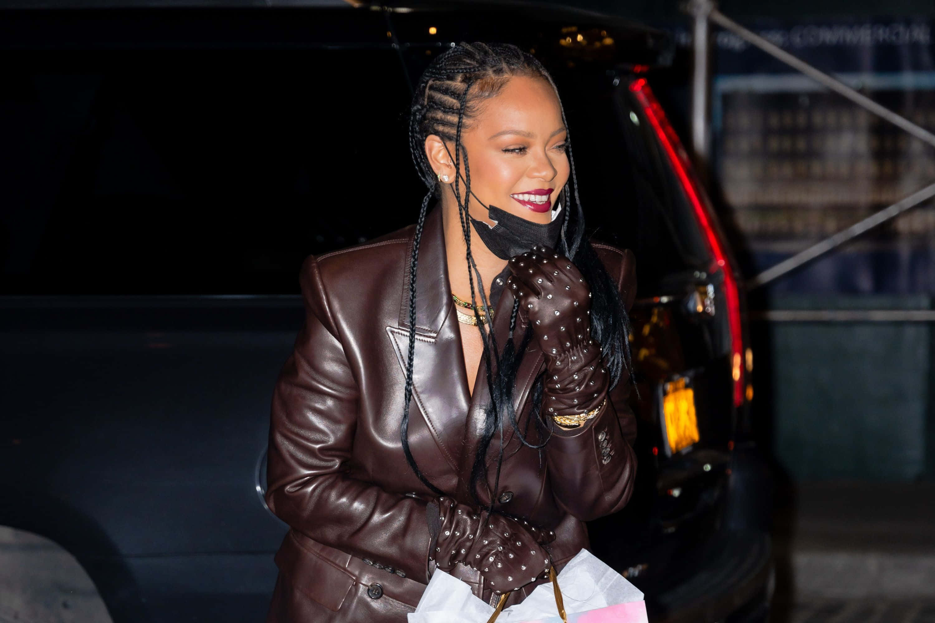 Hairstyle 桌布 壁紙 — Rihanna 在夜晚的車旁微笑，身穿棕色皮夾克和飾釘手套。
