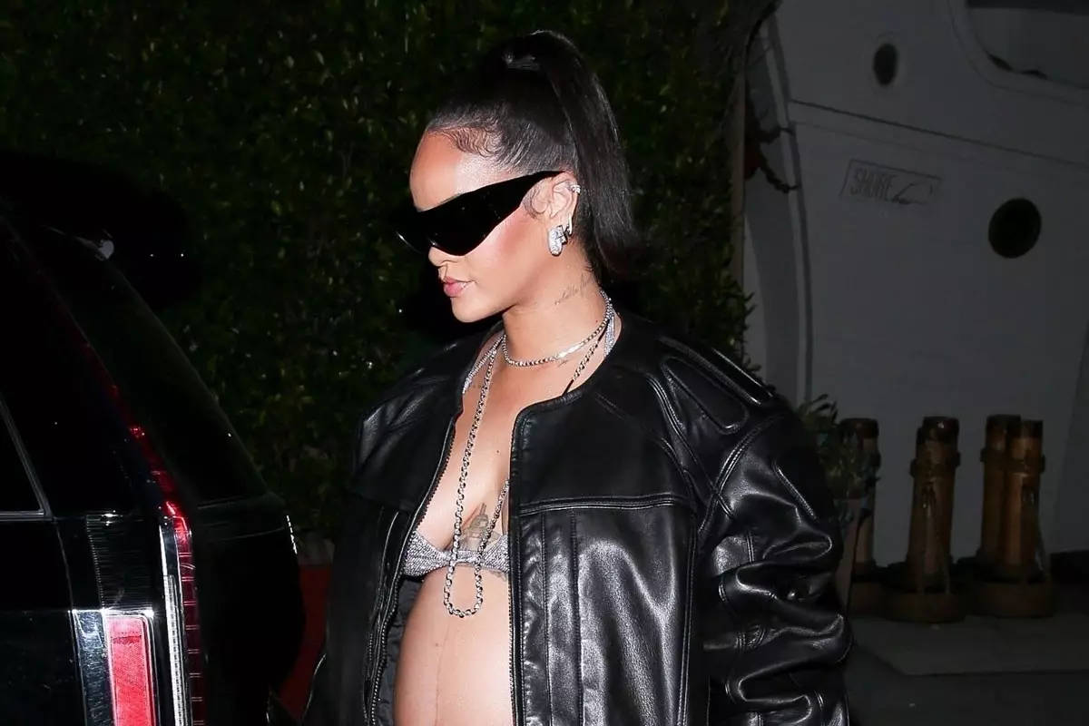 Alexander Wang 桌布 壁紙 — Rihanna 在夜晚自信地穿著黑色皮夾克和太陽眼鏡行走，身後有汽車和綠植。