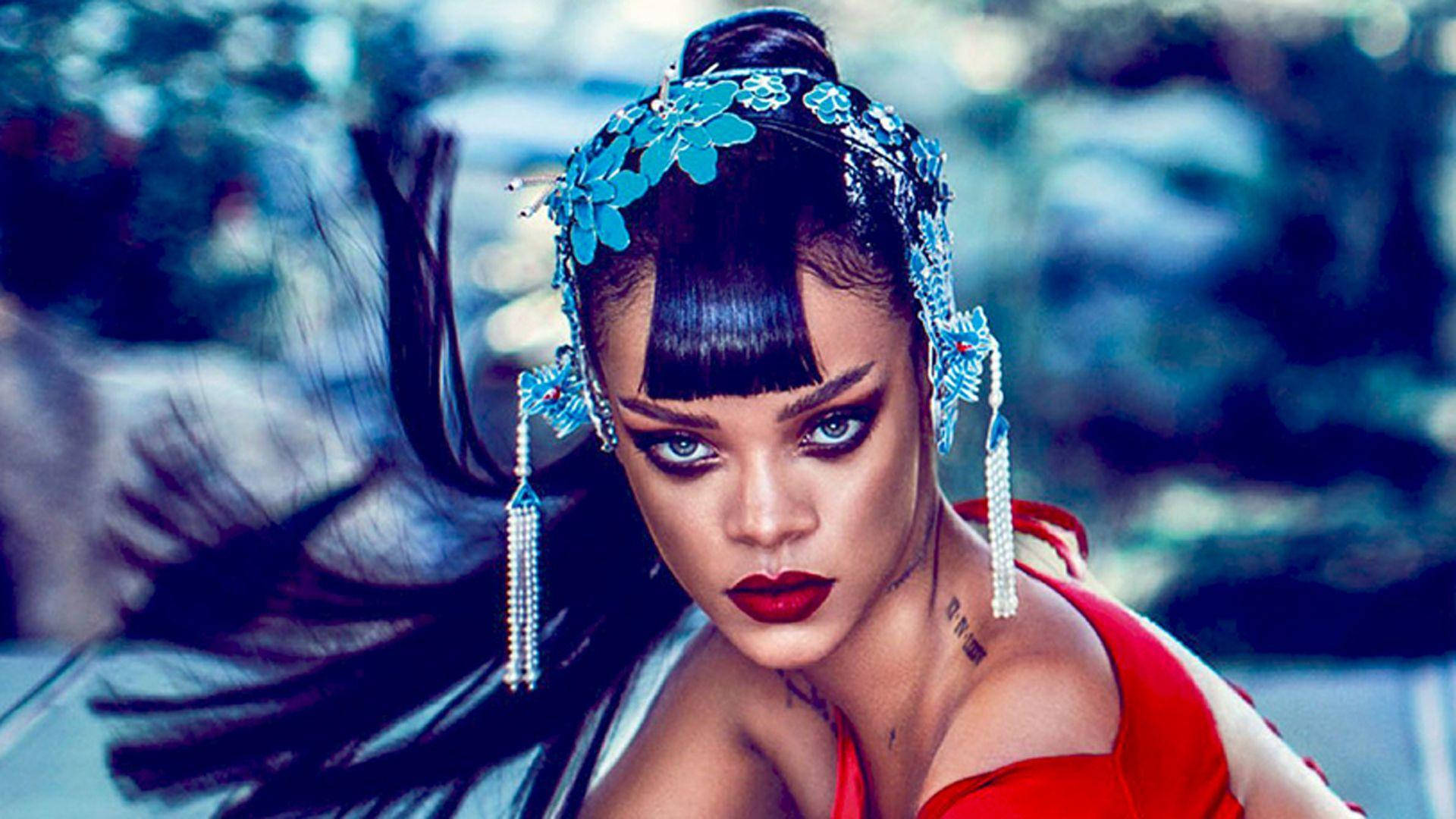 Celebrity 桌布 壁紙 — Rihanna 強烈凝視，搭配大膽紅唇和藍色花卉頭飾，背景為模糊的戶外景色。