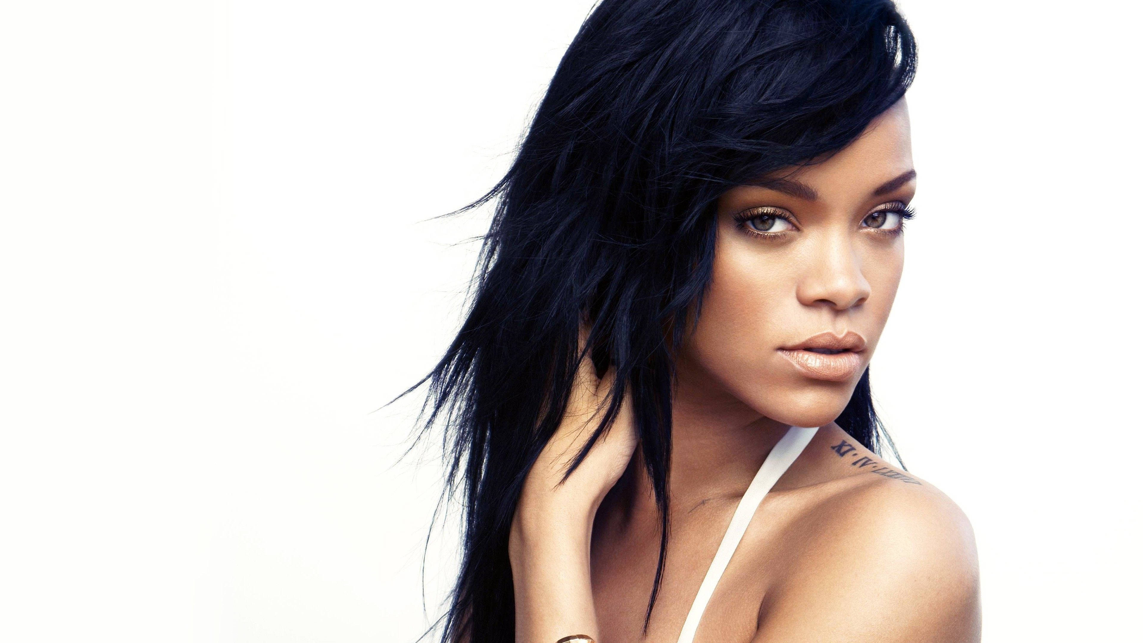蕾哈娜 桌布 壁紙 — Rihanna 的搶眼肖像，深色頭髮，大膽眼神，純白背景。