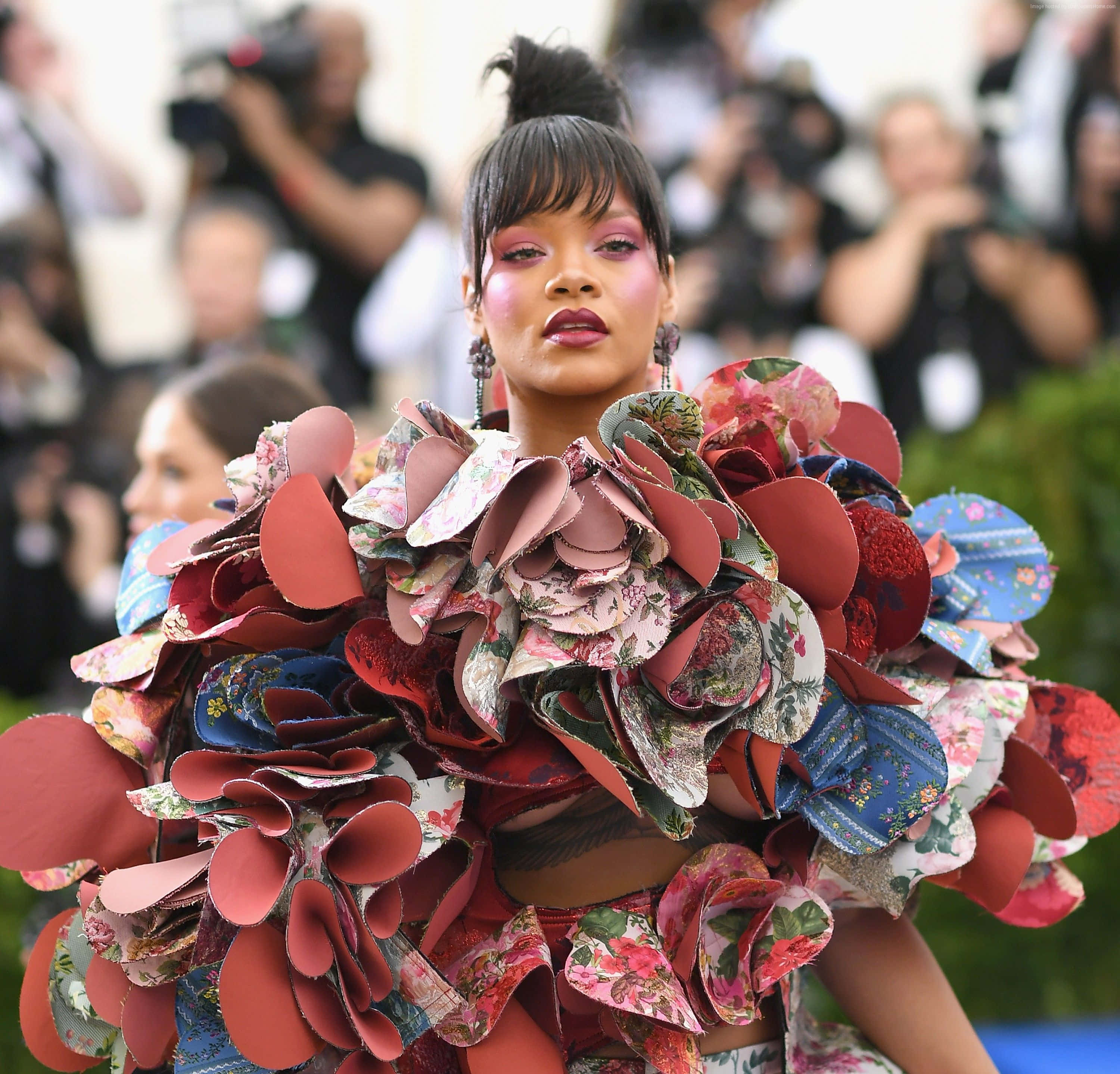 Met Gala 桌布 壁紙 — Rihanna 穿著大膽的花卉和紅色布料荷葉邊禮服，在一個華麗的戶外活動中，背景有攝影師。