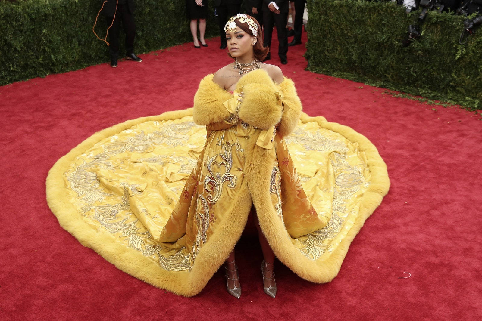 桌布 壁紙 — Rihanna 自信地站在紅地毯上，身穿一件奢華的金色長袍，飾有毛皮邊飾和精緻刺繡。