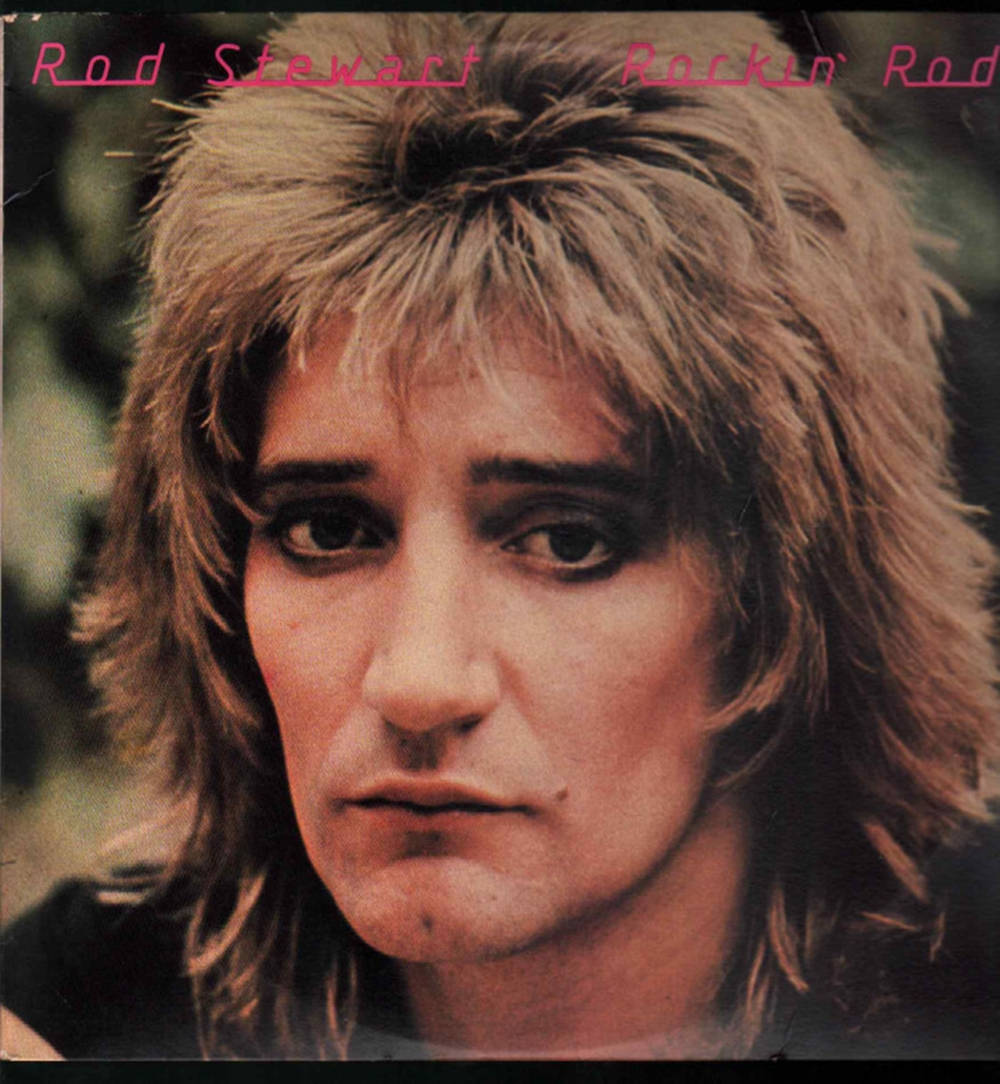Rockstar 桌布 壁紙 — Rod Stewart 的頭像特寫，頭髮蓬鬆金黃，眼神銳利，背景模糊綠色。