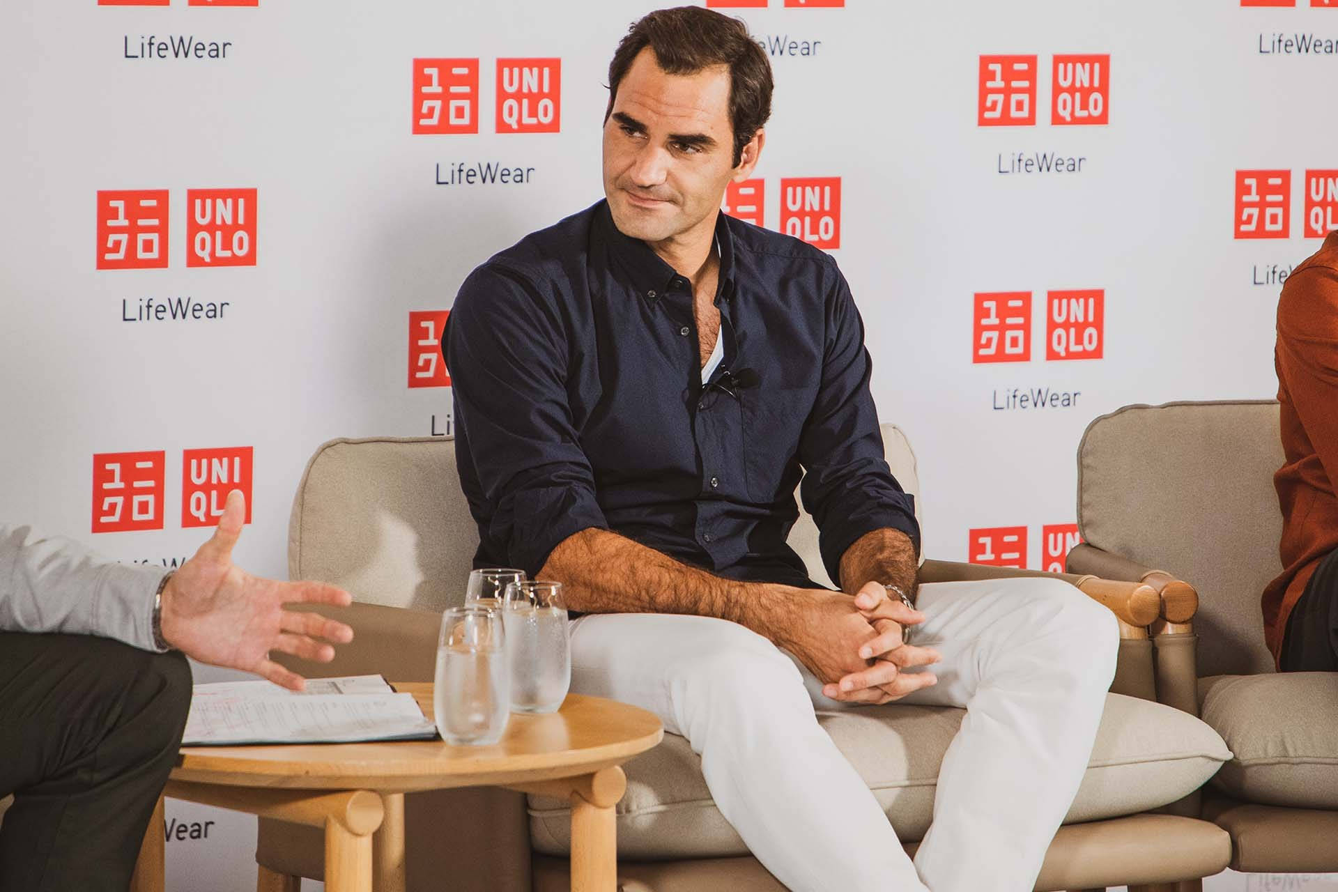 roger 桌布 壁紙 — Roger Federer 冷靜地坐在米色扶手椅上，雙手緊握，接受 UNIQLO LifeWear 訪問，旁邊另一個人正在做手勢。