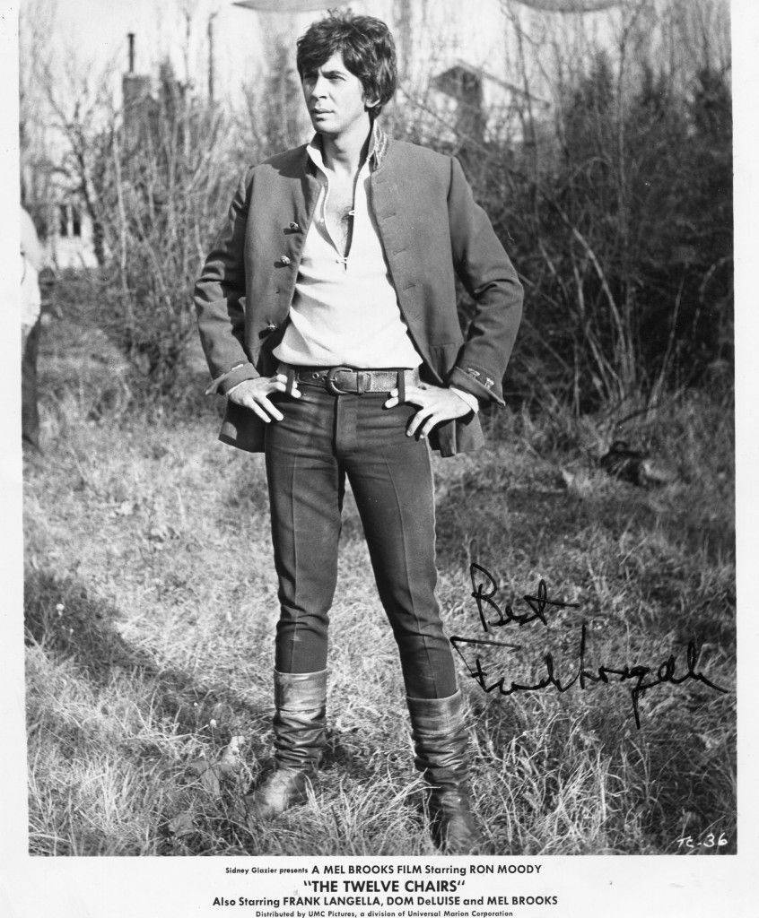 Celebrity 桌布 壁紙 — Ron Moody 自信地穿著復古外套和靴子，站在草地上，身後有光禿禿的樹木，這是一張黑白電影劇照。