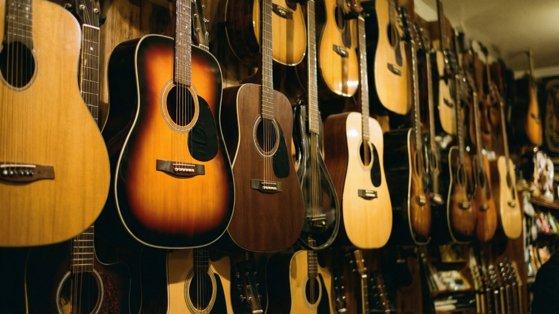 Guitar Gallery 壁紙 — 一排排木吉他緊密地掛在木牆上，沐浴在溫暖的金色光芒中。
