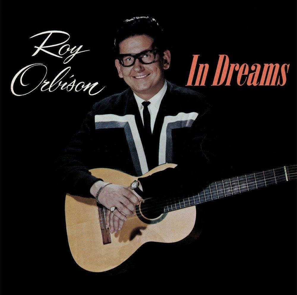 Retro 桌布 壁紙 — Roy Orlison 溫暖地微笑，手持木吉他，背景為純黑色，並有專輯標題文字。