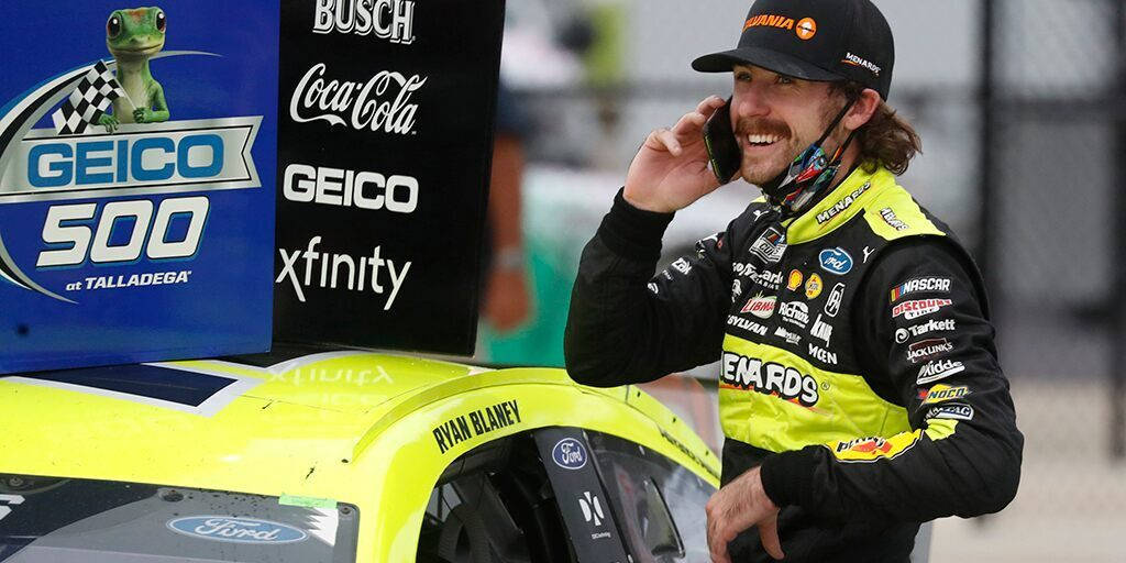Ryan Blaney 桌布 壁紙 — Ryan Blaney 在塔拉迪加他的亮黃色福特賽車旁微笑著講電話。