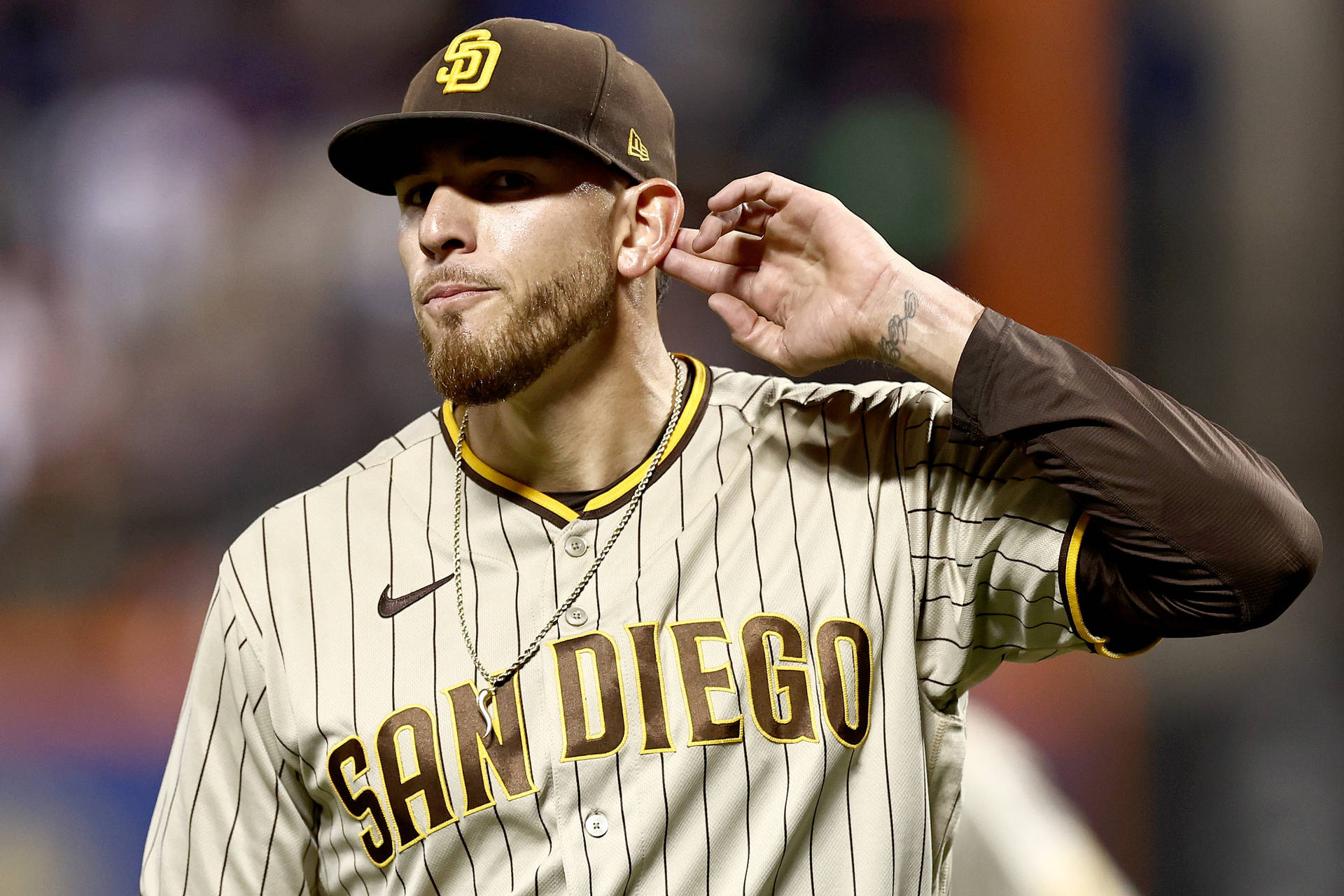 穿著聖地牙哥隊服的棒球選手在夜間比賽中調整耳朵。 — MLB 壁紙